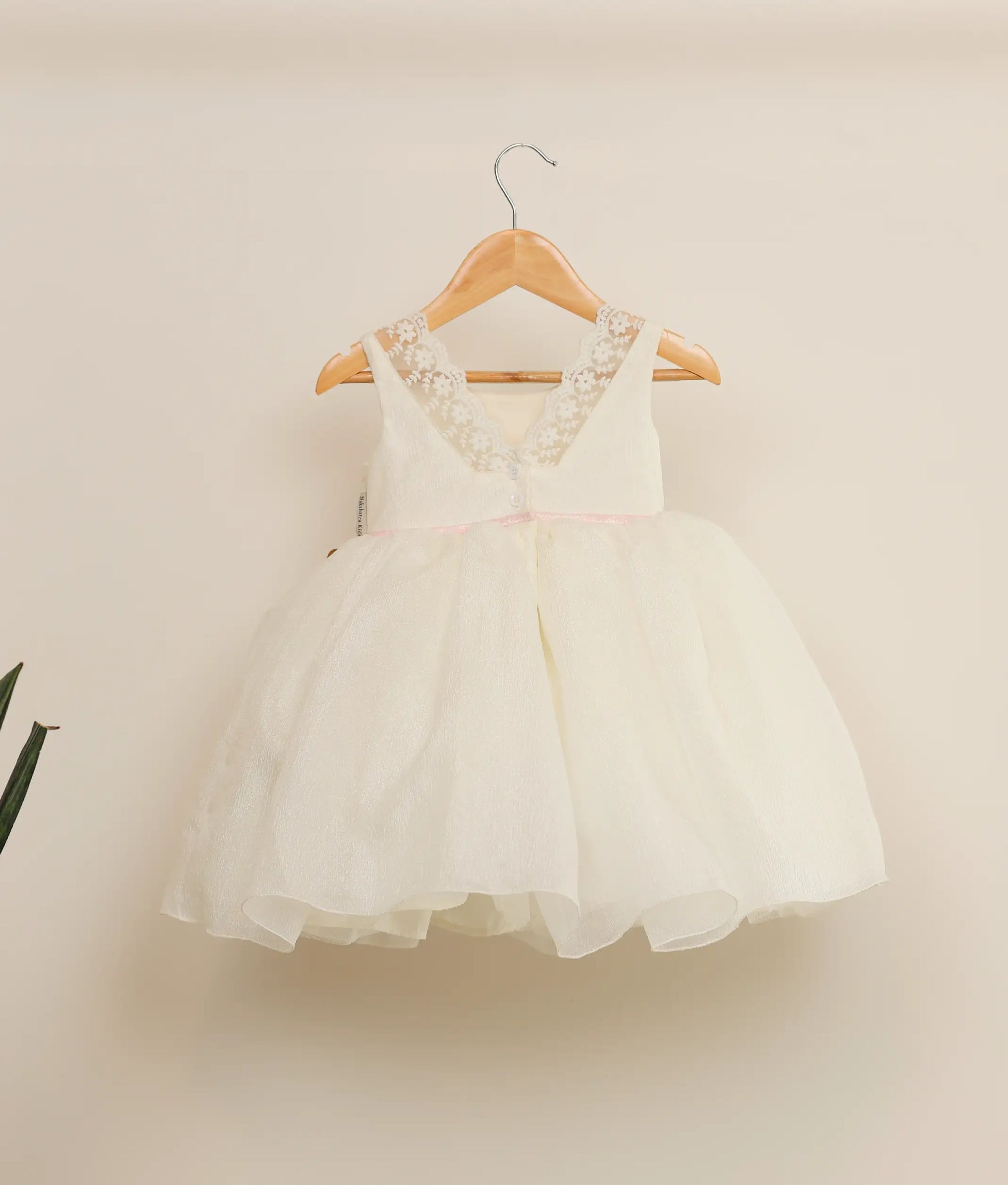 Back view of crush organza floral handwork birthday dress against plain background