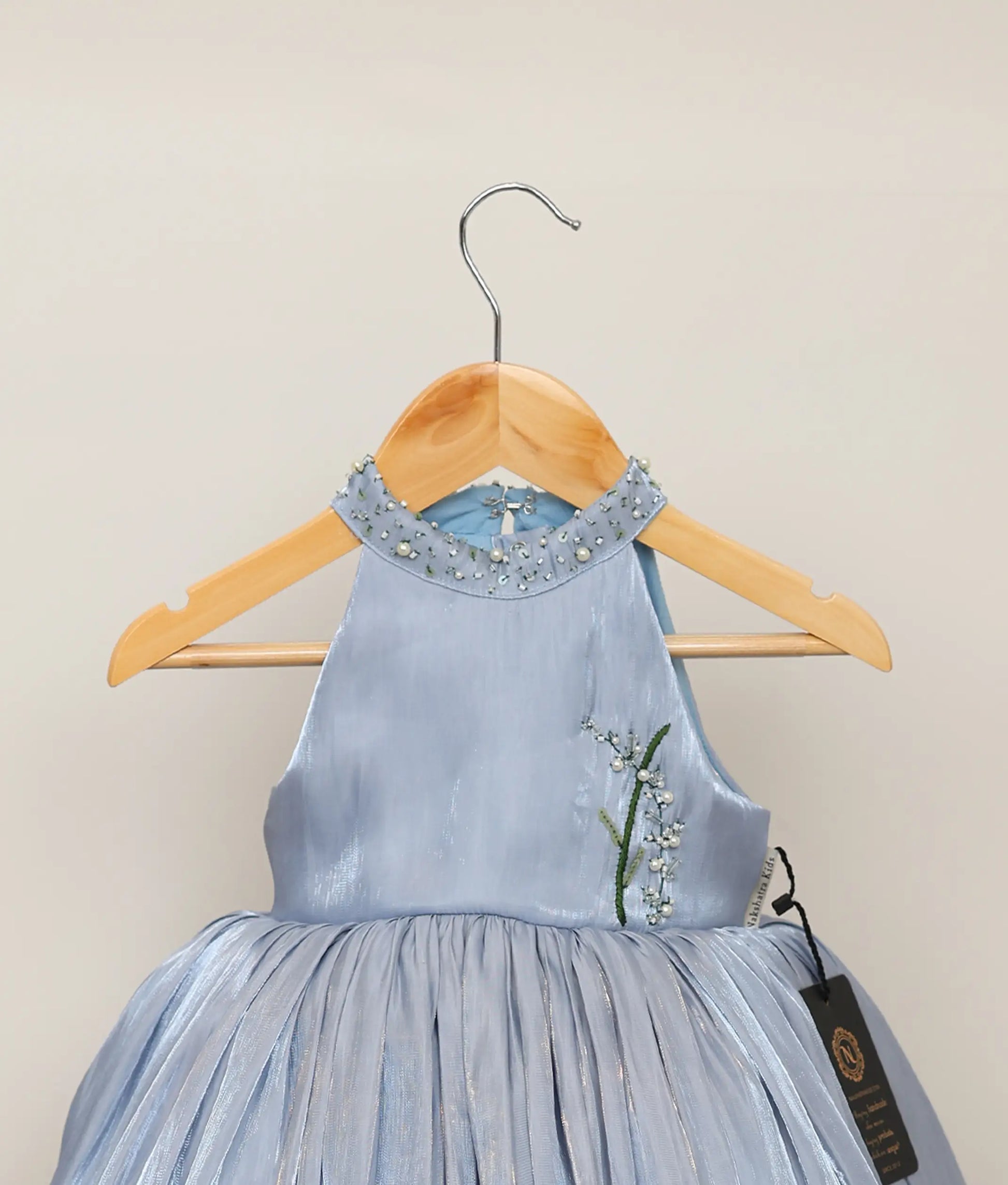 Close view of ash blue laser organza floral, handworked birthday frock against plain background