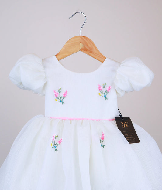 Close  view of an handworked floral-themed dress against white background 