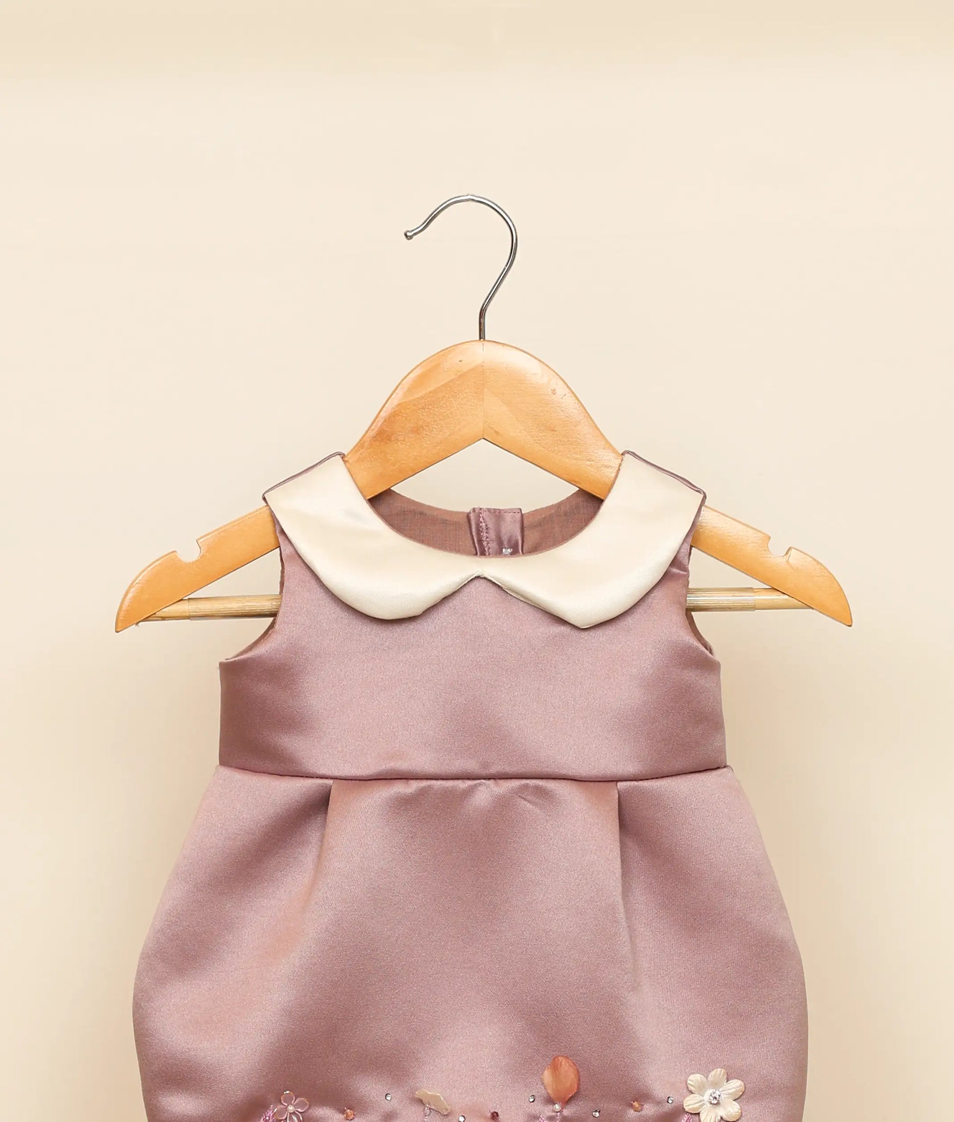 Close view of a pastel lavender handworked fish-cut frock against plain ground 