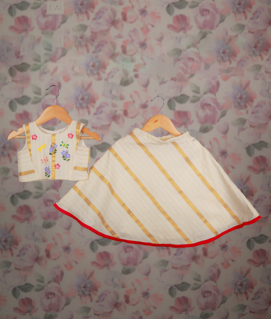 A floral hand-painted top and a golden striped skirt with a red border hem.