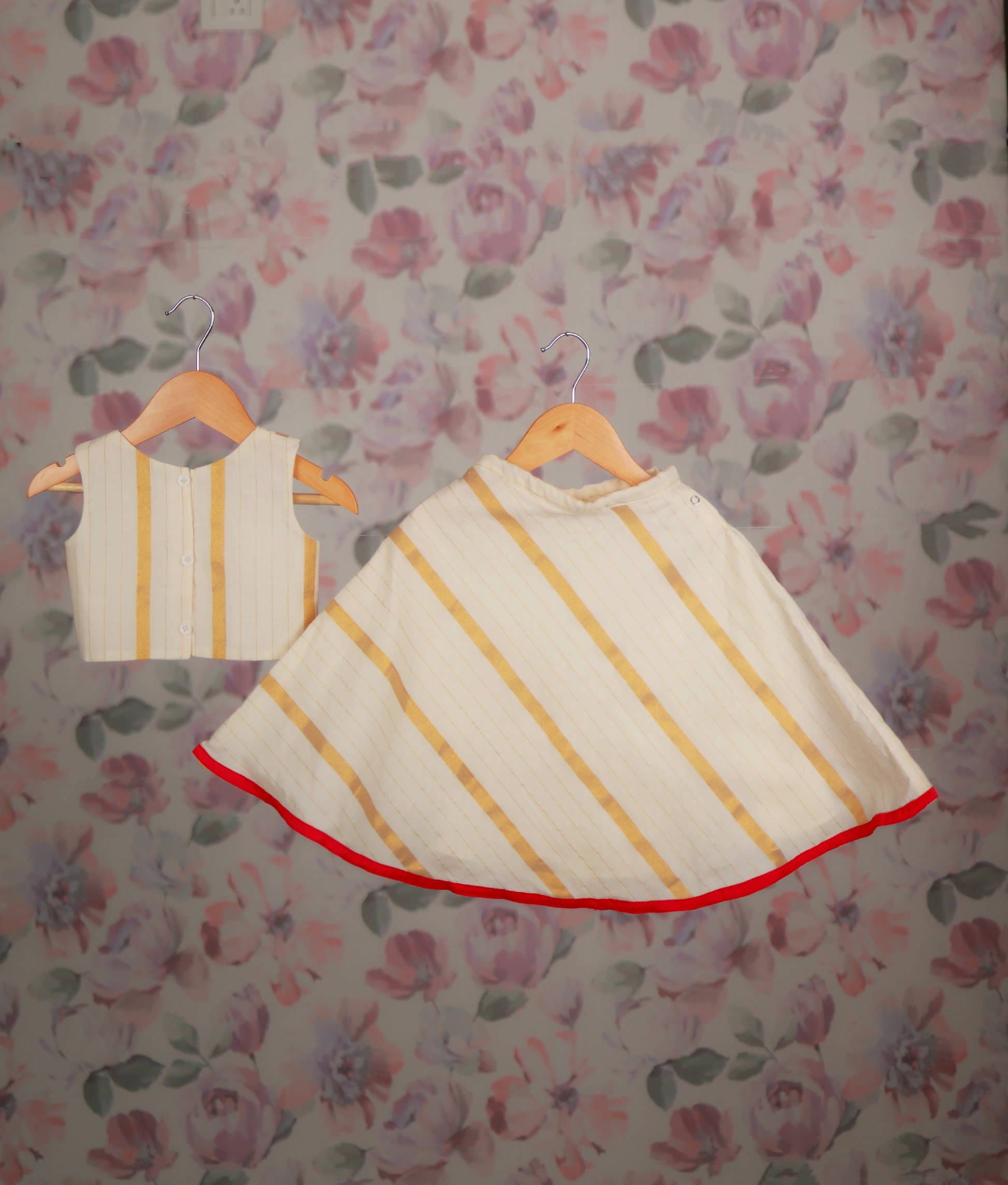 Back view of a floral hand-painted top and a golden striped skirt with a red border hem.