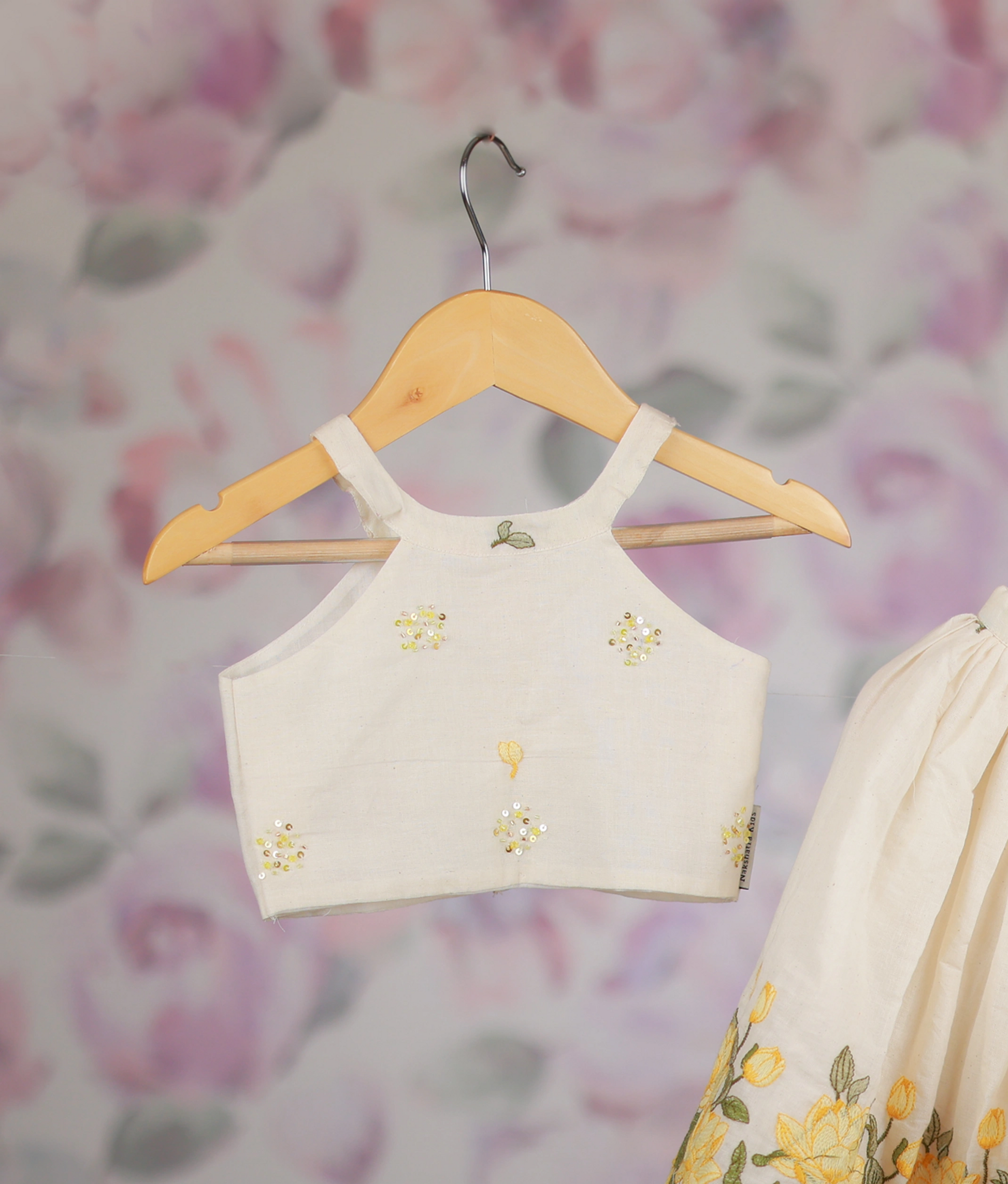 Off-white kids' outfit with a floral embroidered crop top and a yellow lotus border skirt set.
