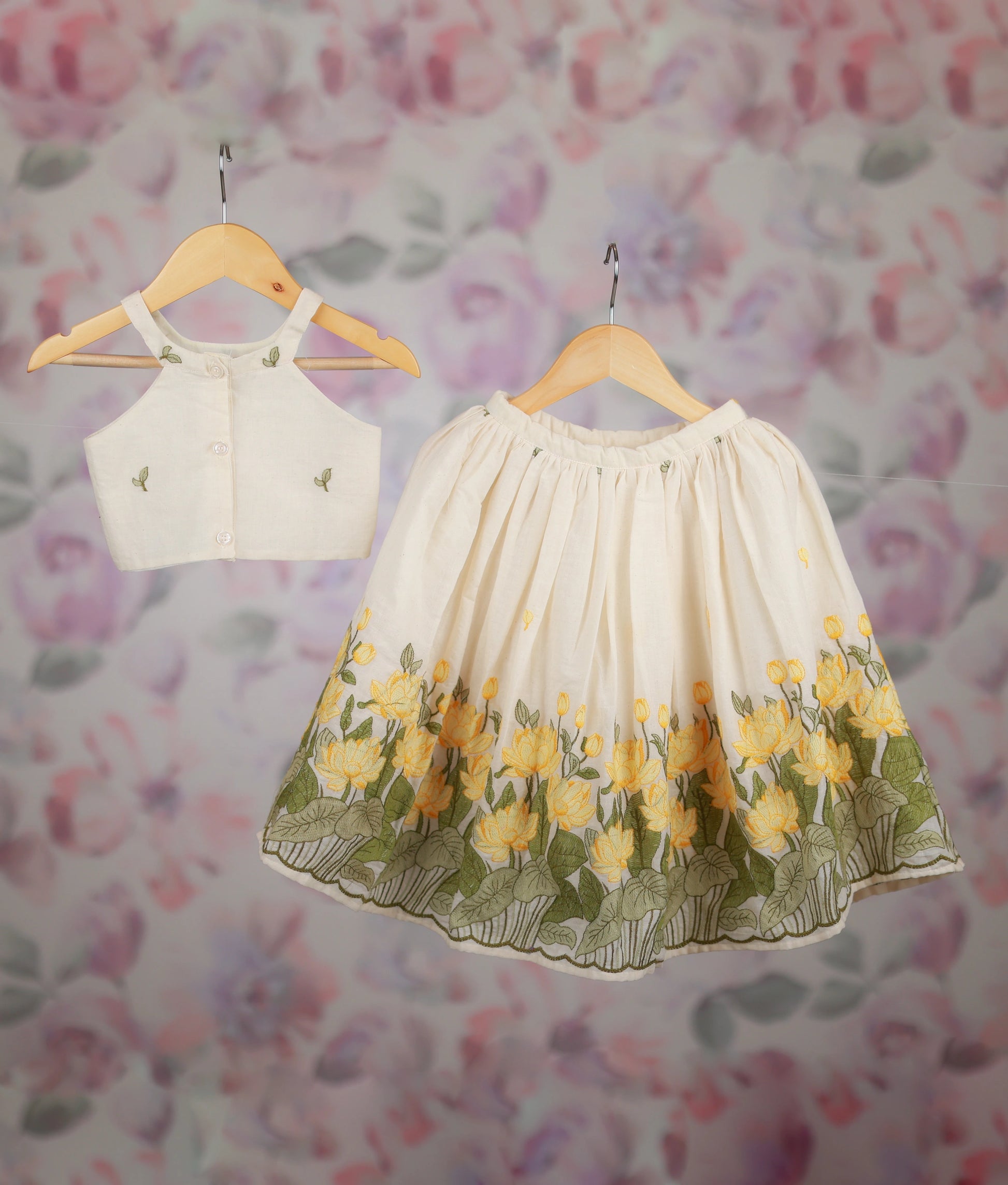 Back view of an off-white kids' outfit with a floral embroidered crop top and a yellow lotus border skirt set.
