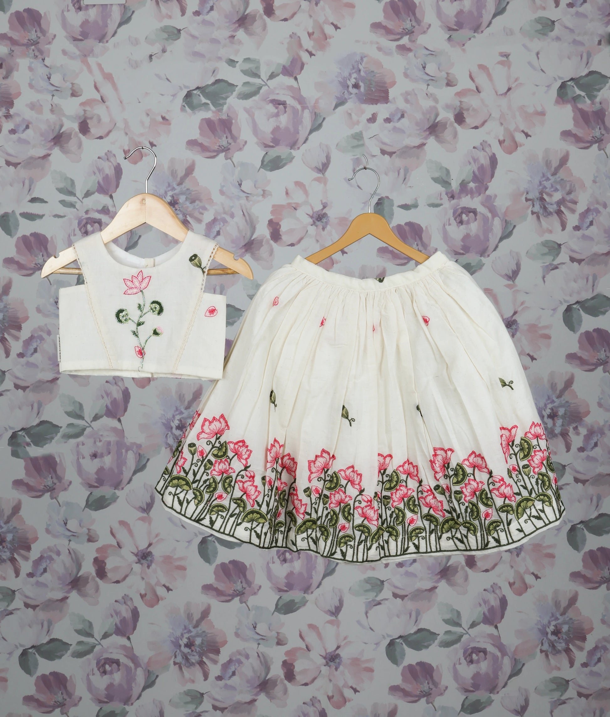 Off-white floral handworked short top and skirt set for girls with pink lotus design pattern.