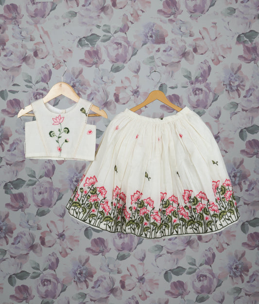 Off-white floral handworked short top and skirt set for girls with pink lotus design pattern.