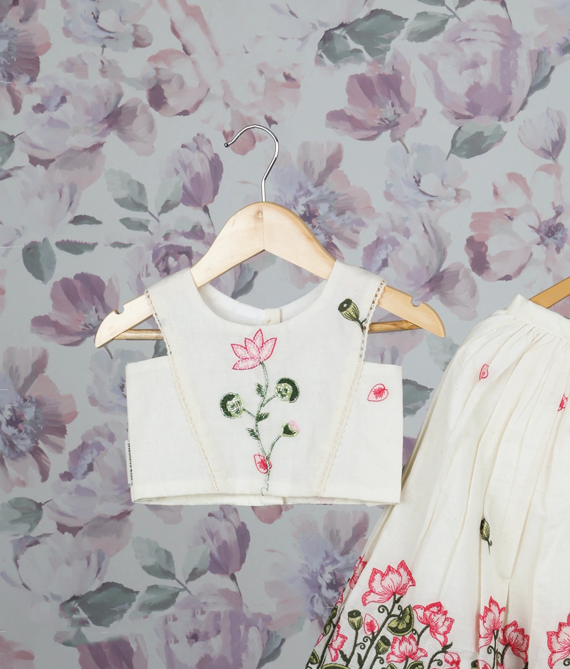 Close view of an off-white floral handworked short top and skirt set for girls with pink lotus design pattern.
