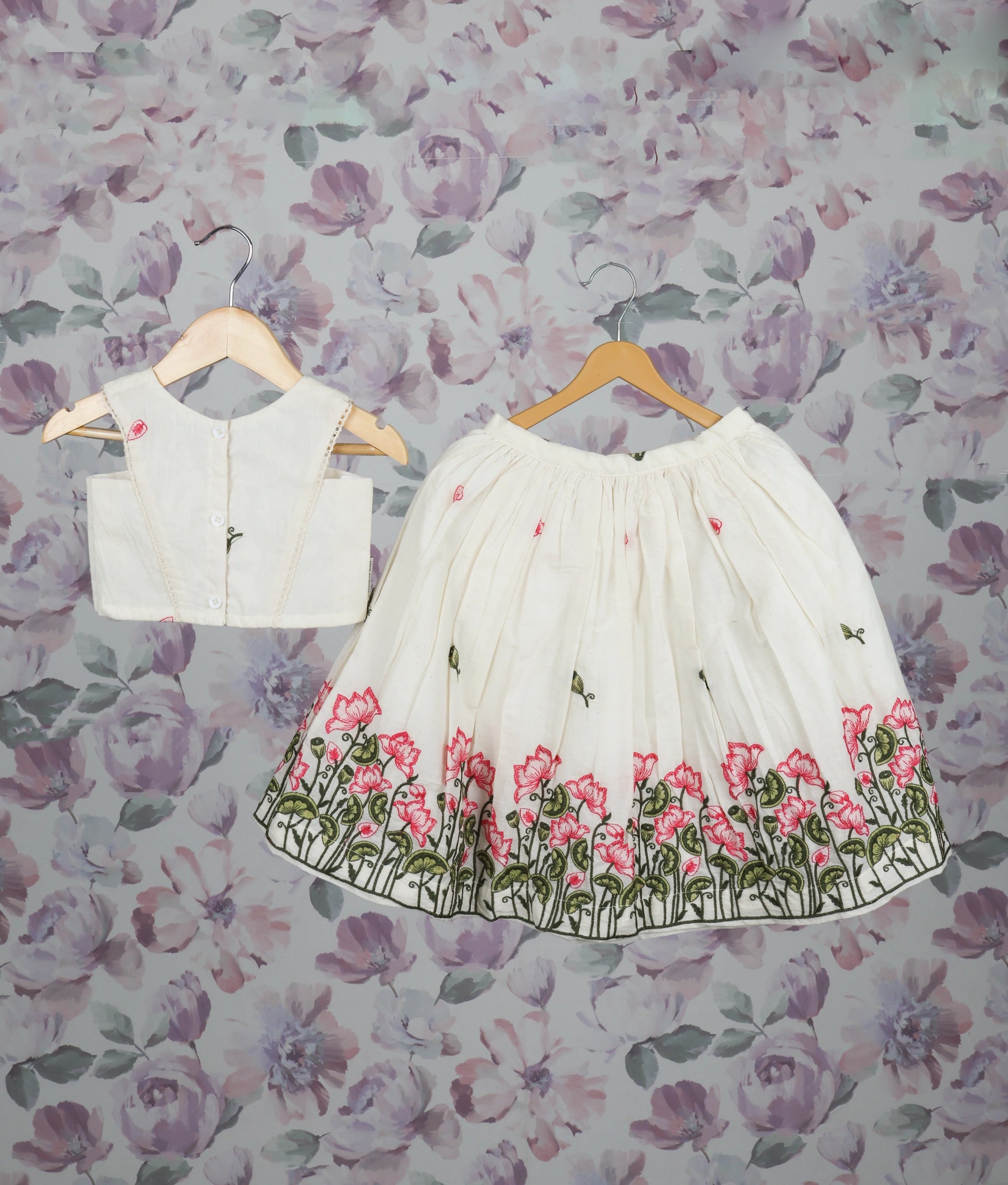 Back view of an off-white floral handworked short top and skirt set for girls with pink lotus design pattern.