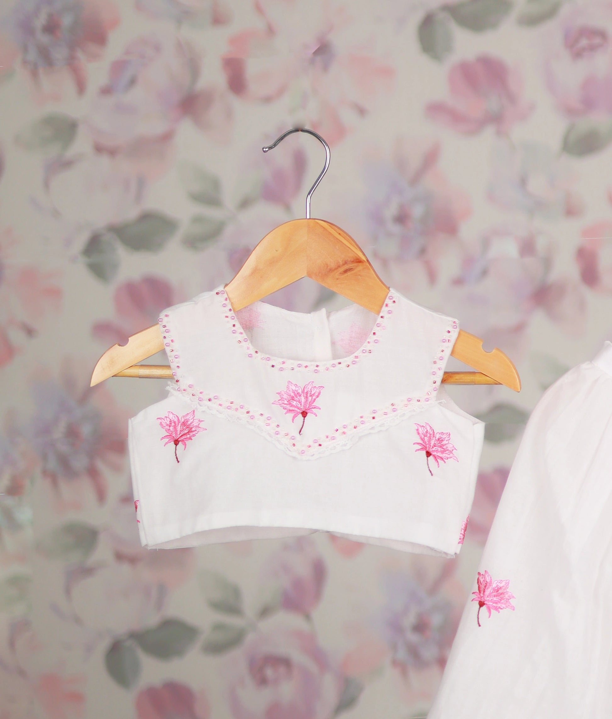 Close view of a white baby girl skirt set with a pink floral embroidery top and ethnic outfit.