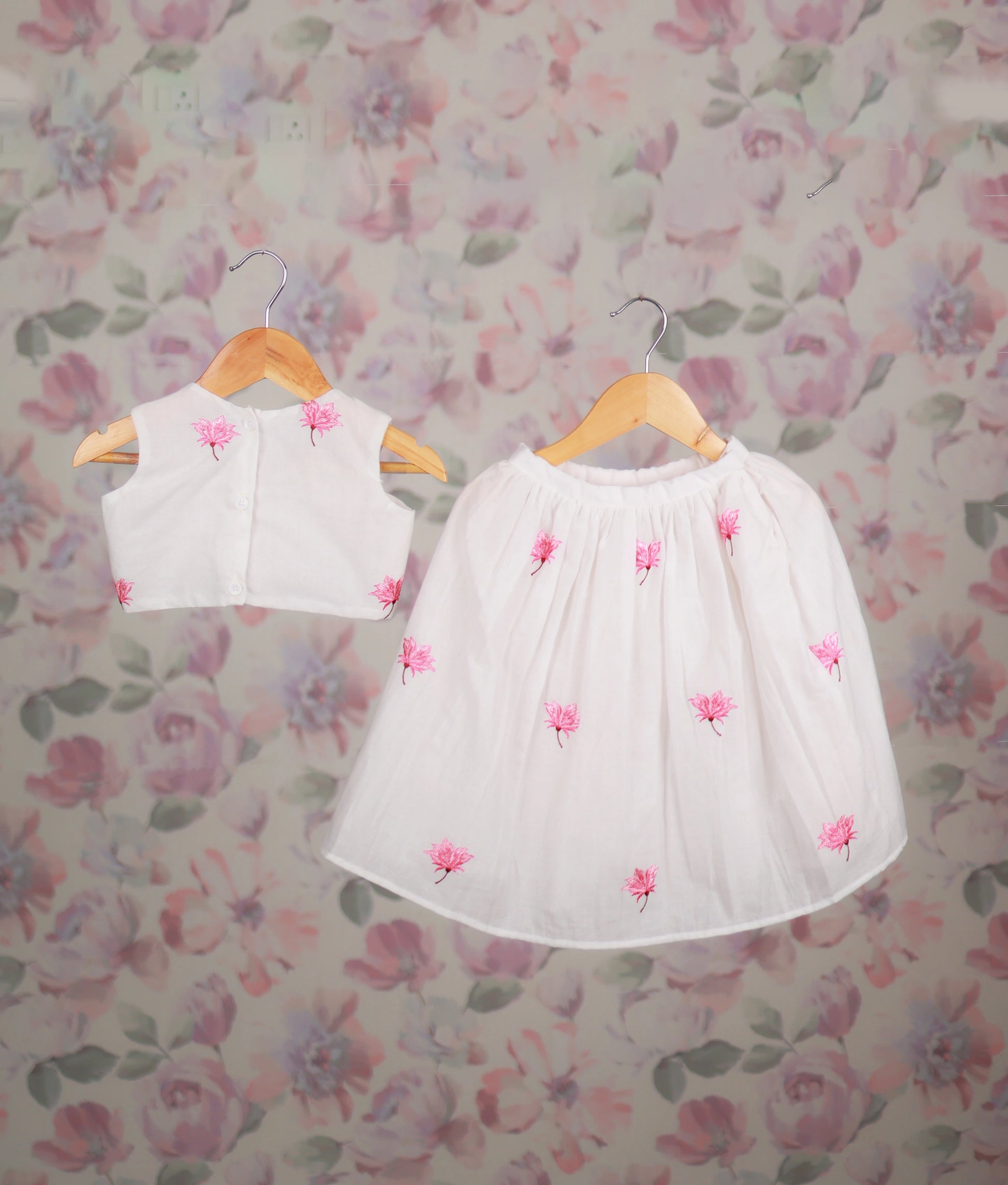 Back view of a white baby girl skirt set with a pink floral embroidery top, an ethnic outfit.