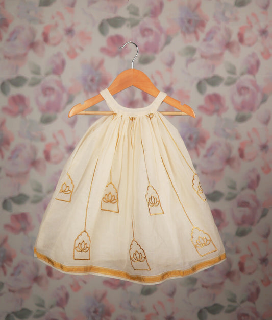 Off-white gold lotus embroidery frock on a wooden hanger against a floral background.