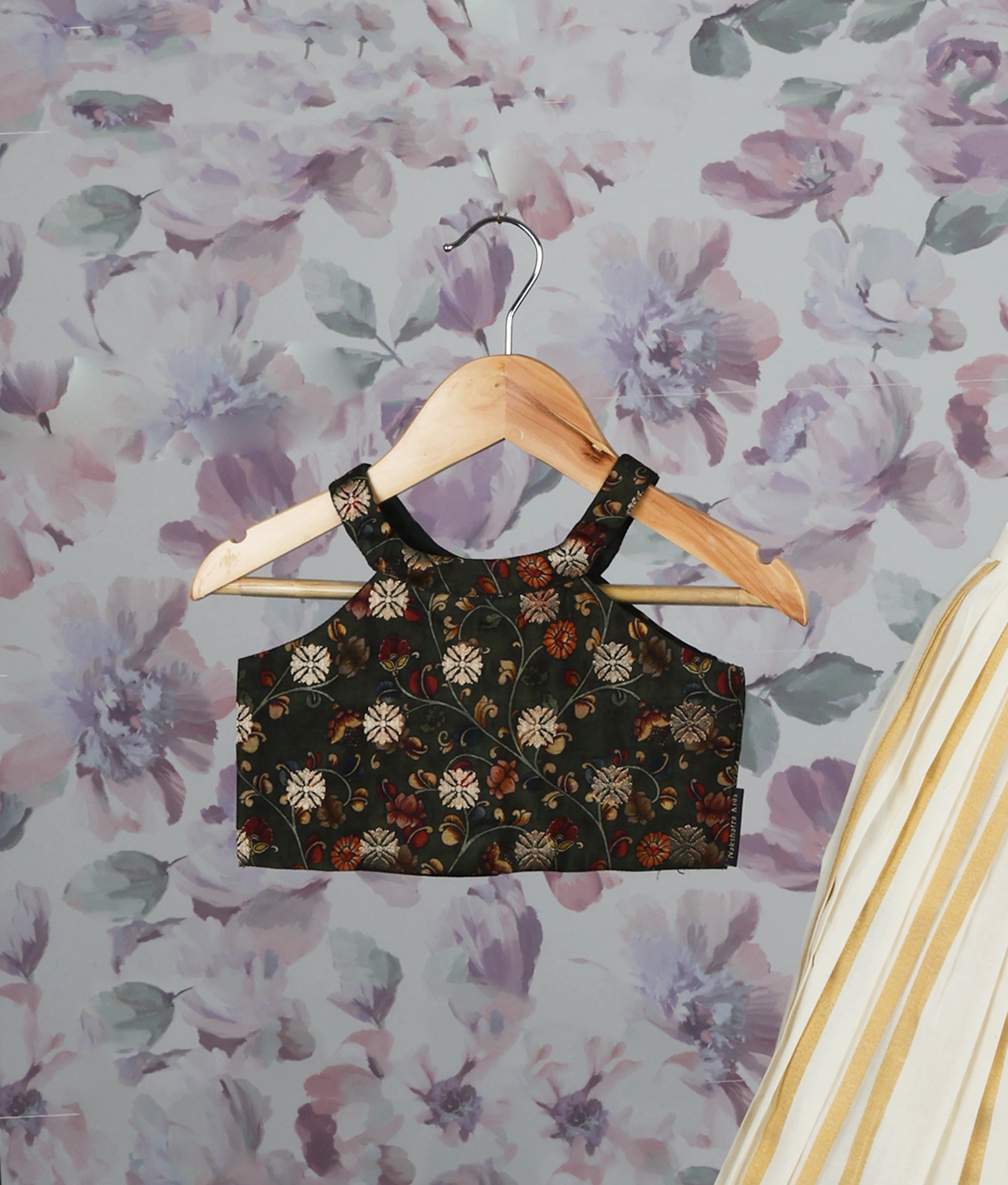 Close view of a floral green crop top and golden striped pleated skirt set against a floral background.
