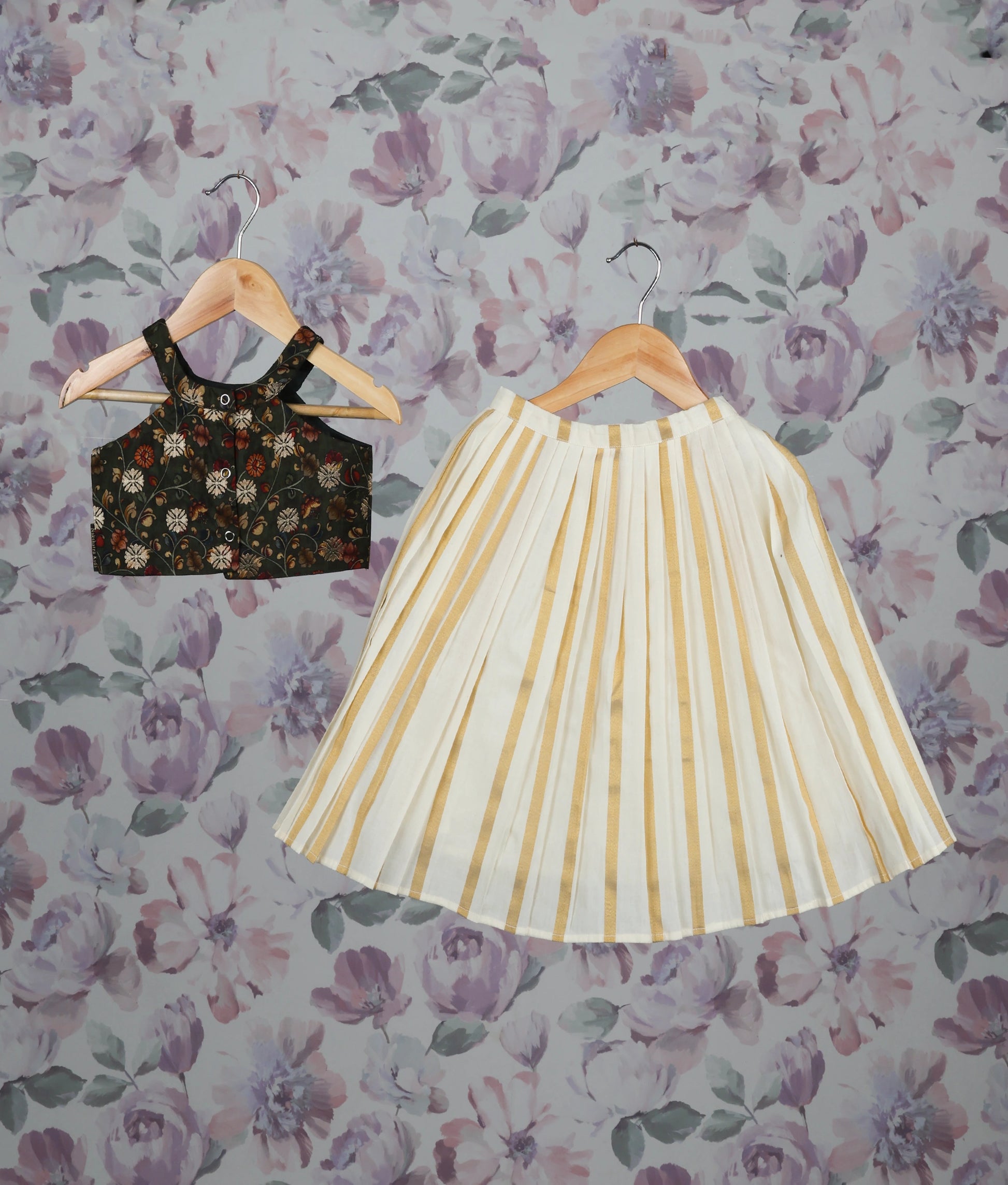 Back view of a floral green crop top and golden striped pleated skirt set against a floral background.