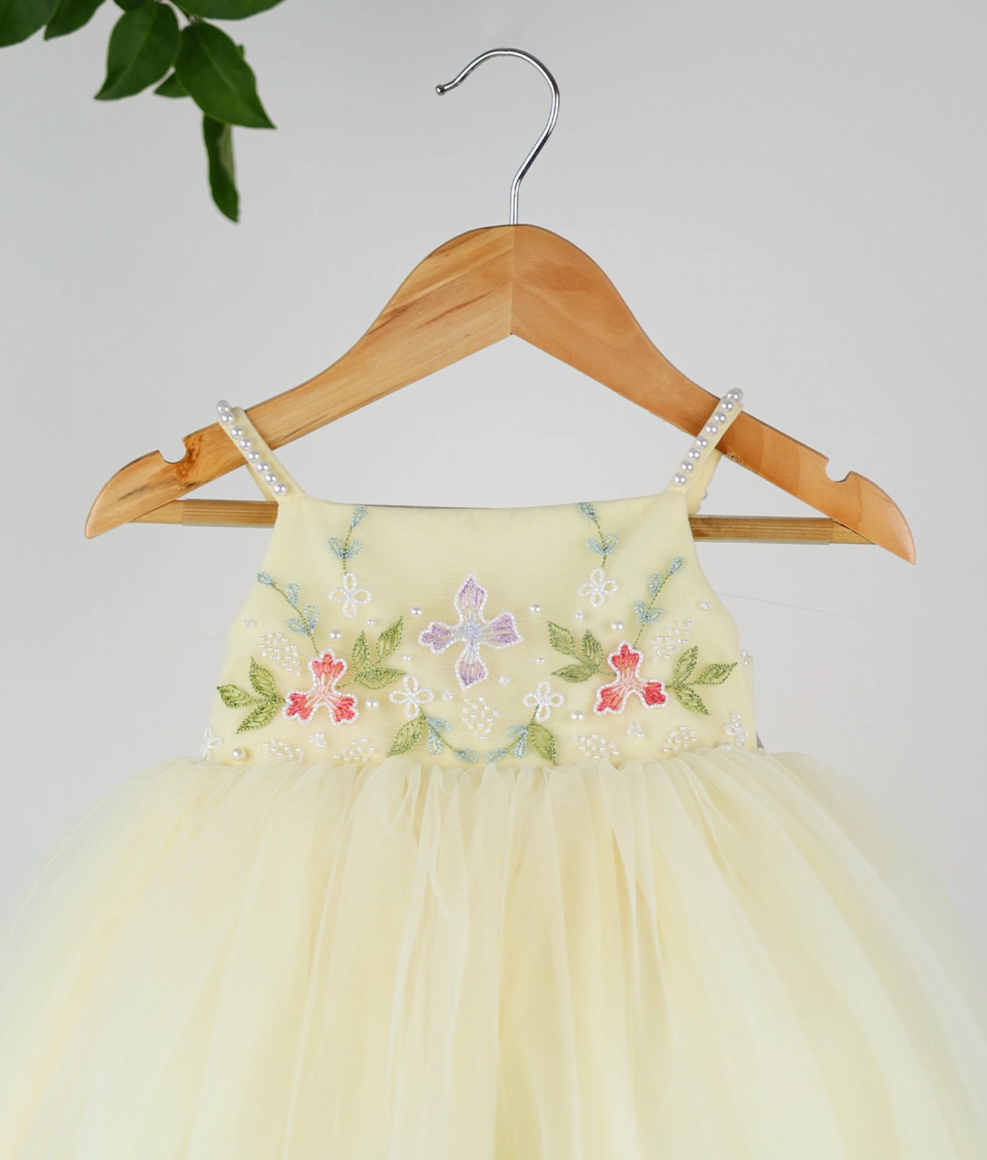 Close view of a pastel yellow tulle net floral handworked birthday frock.