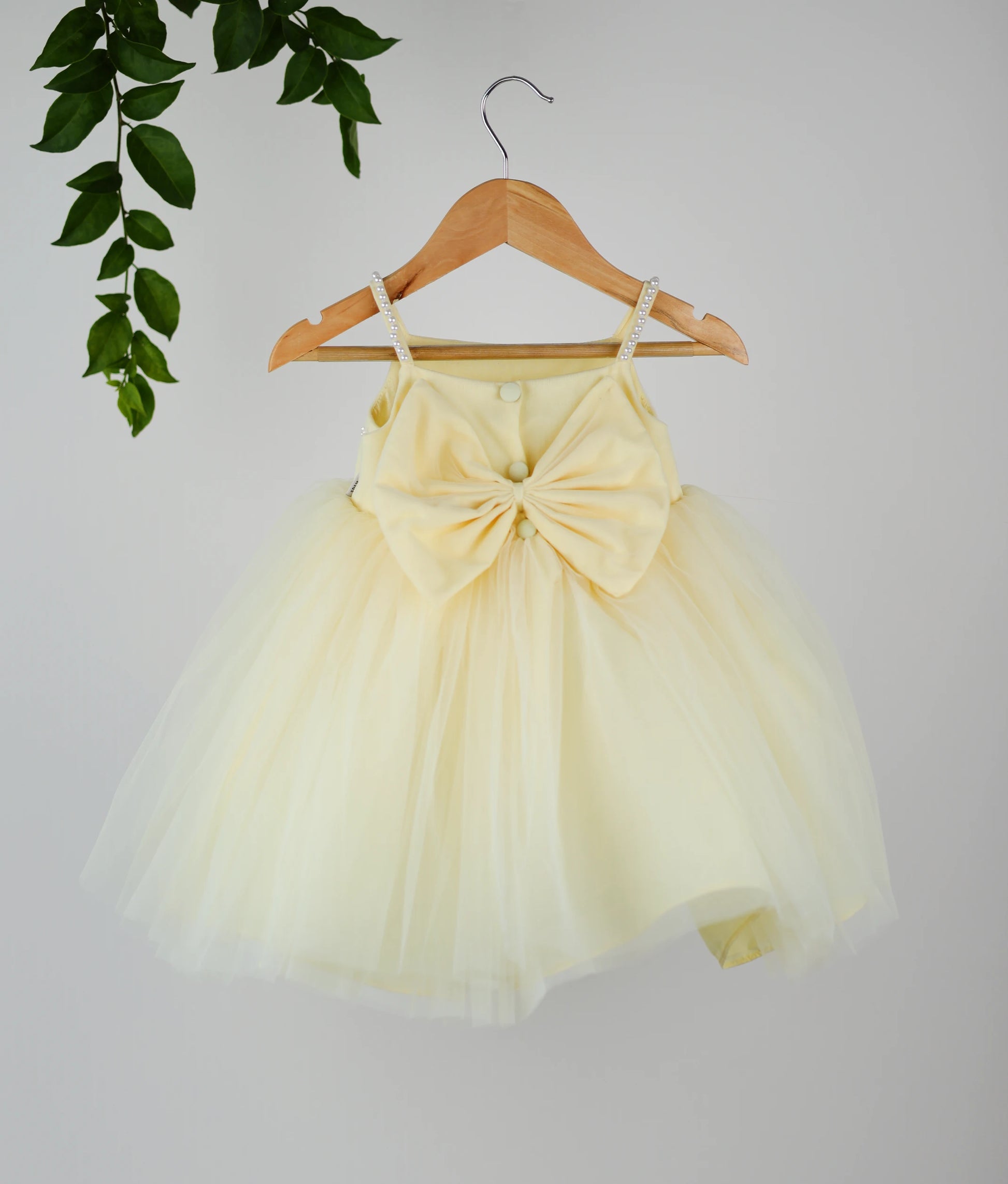 Back view of a pastel yellow tulle net floral handworked birthday frock.
