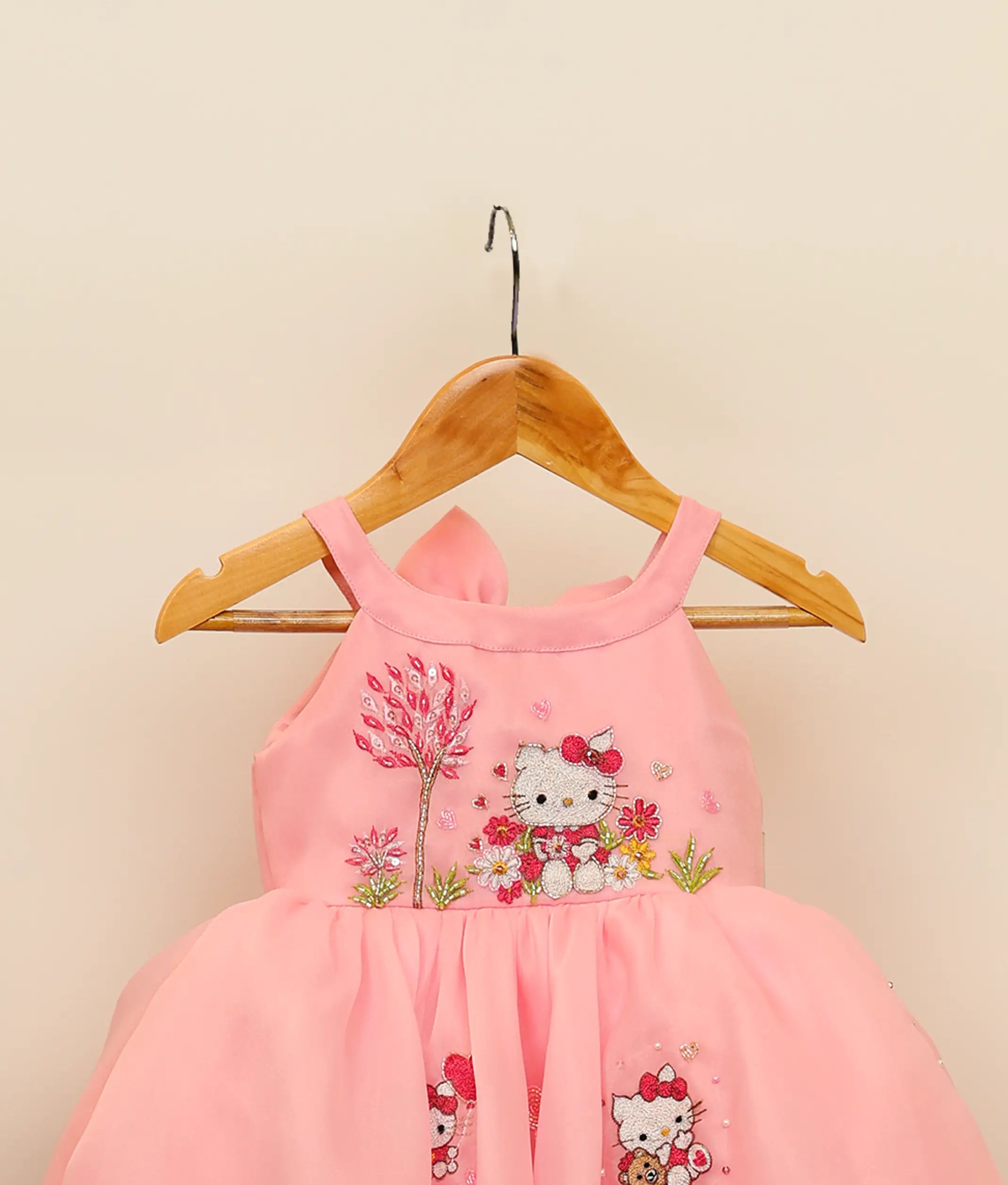 Close view of embroidery kitty-themed dress for baby girl against plain background