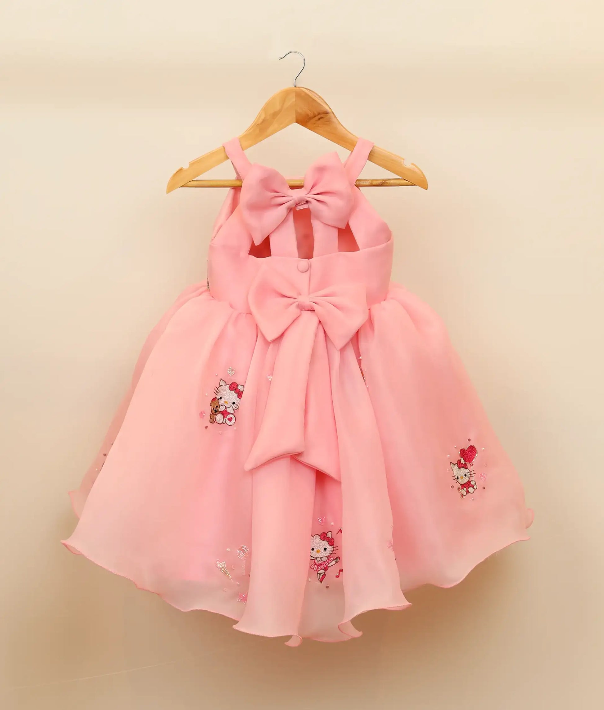 Back view of embroidery kitty-themed dress for baby girl against plain background