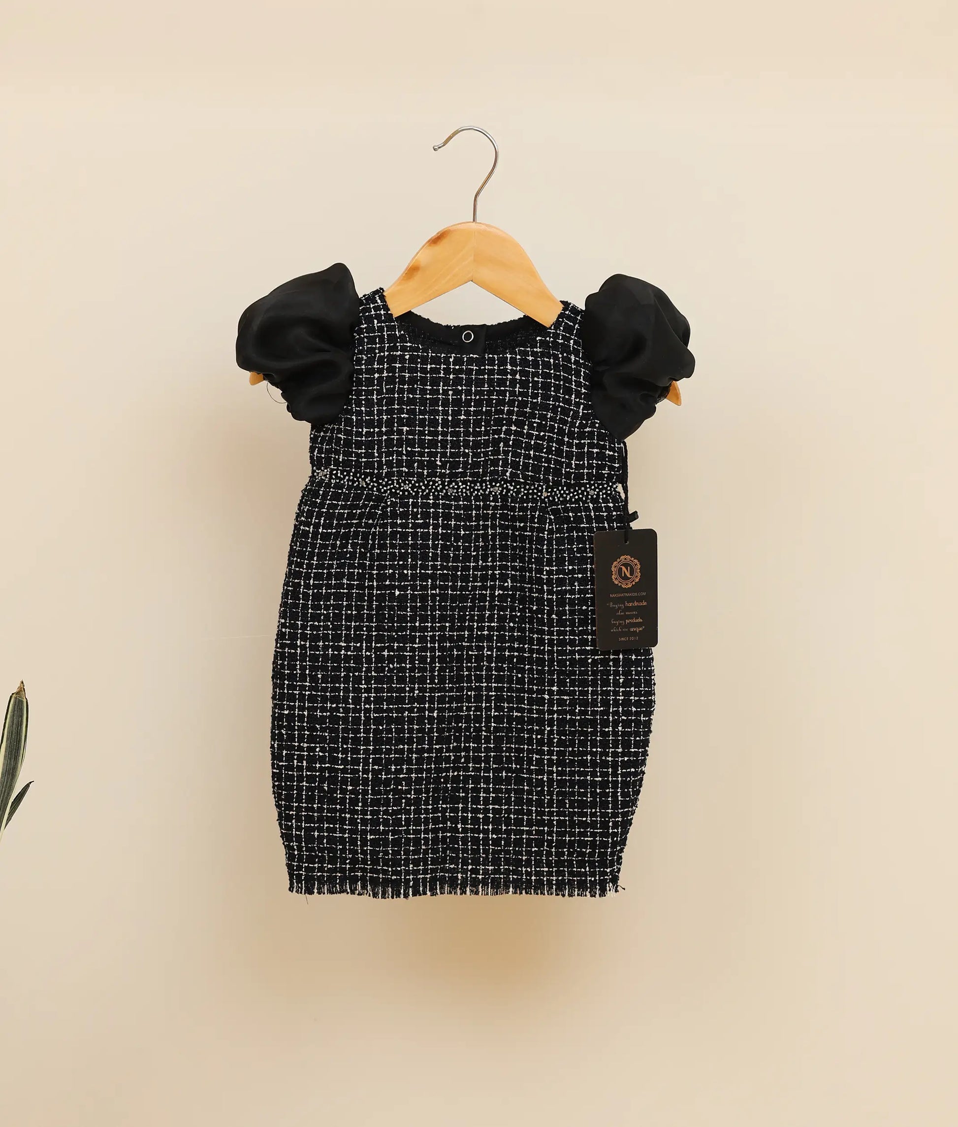 Black tweed handworked fish-cut frock against plain background