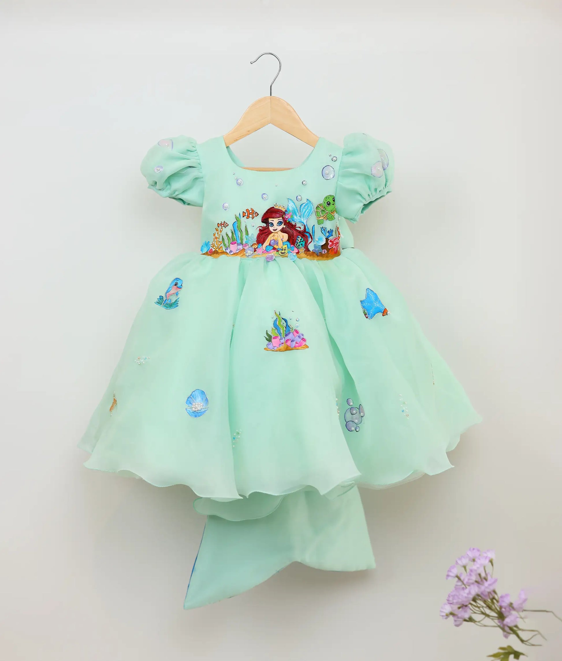 Front view of sea green plain organza painting and handworked mermaid-themed birthday dress against plain background