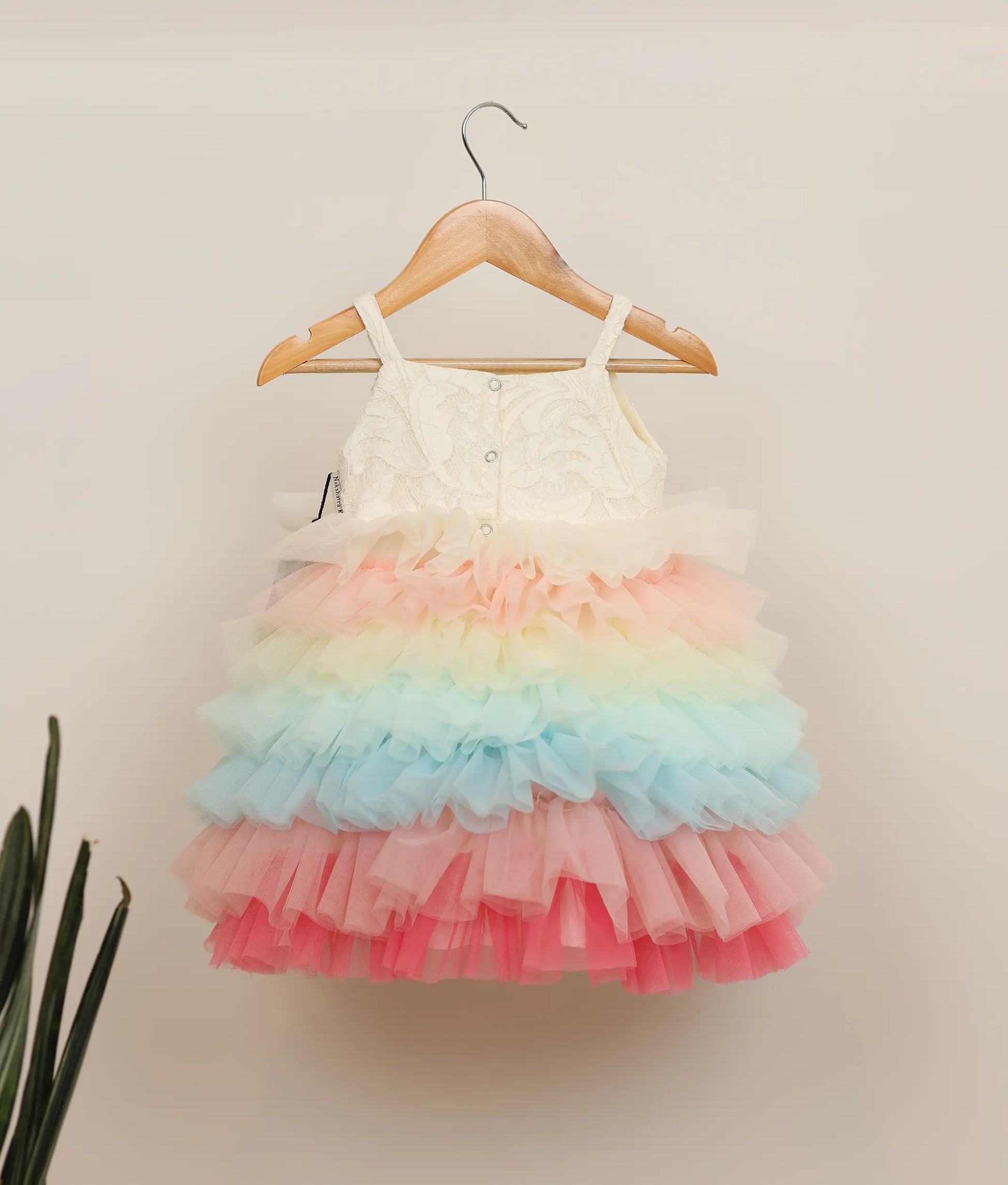 Back view of a multi-color tulle net handworked birthday frock against plain background