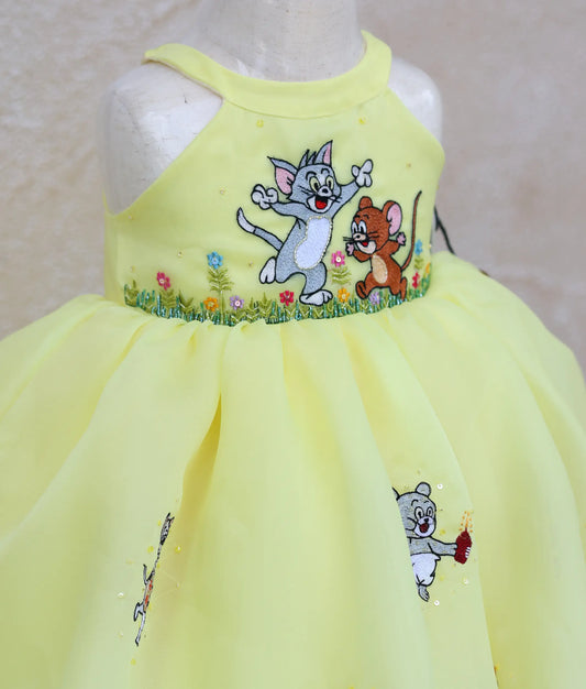 close view of yellow plain organza tom and Jerry-themed birthday dress for baby girl 