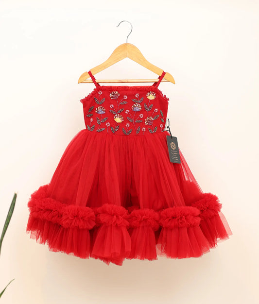 Front view of a handworked tulle net birthday frock against plain background