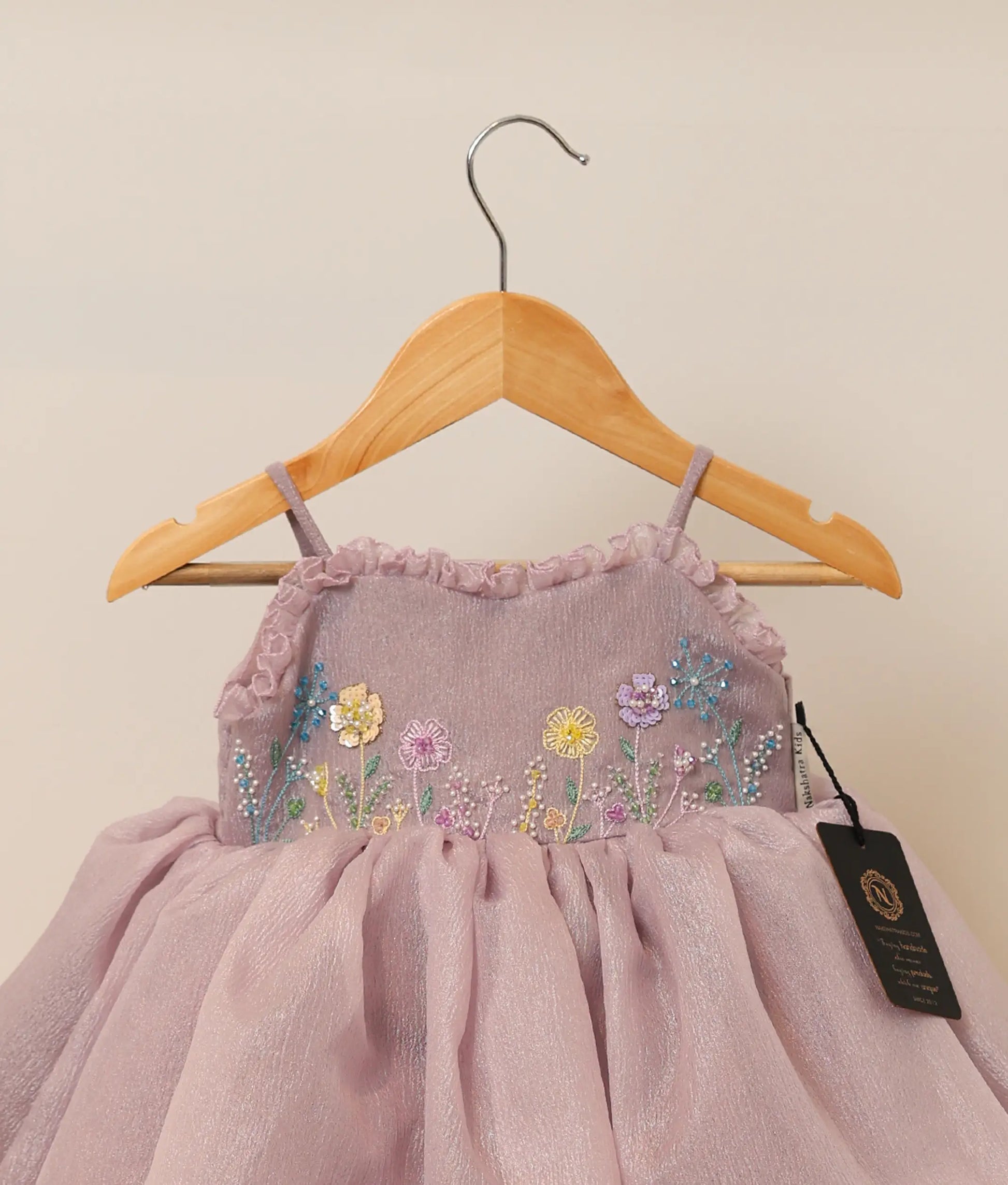 Close view of pastel lavender crush organza flower-themed birthday frock against plain background