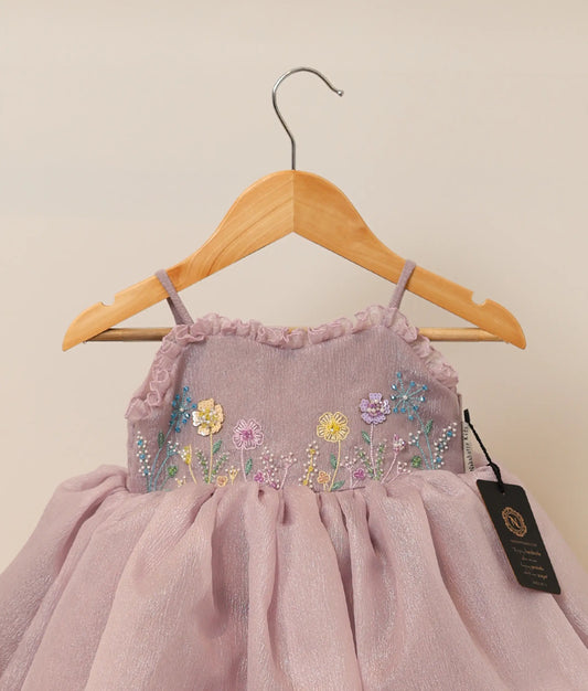 Close view of pastel lavender crush organza flower-themed birthday frock against plain background