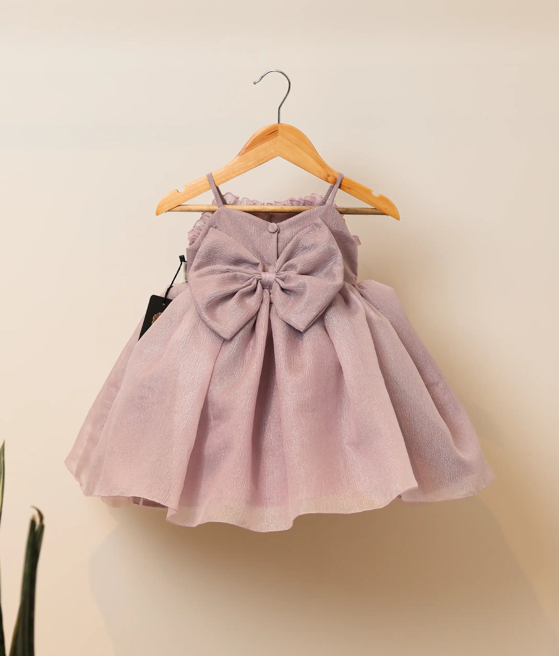 Back view of pastel lavender crush organza flower-themed birthday frock against plain background