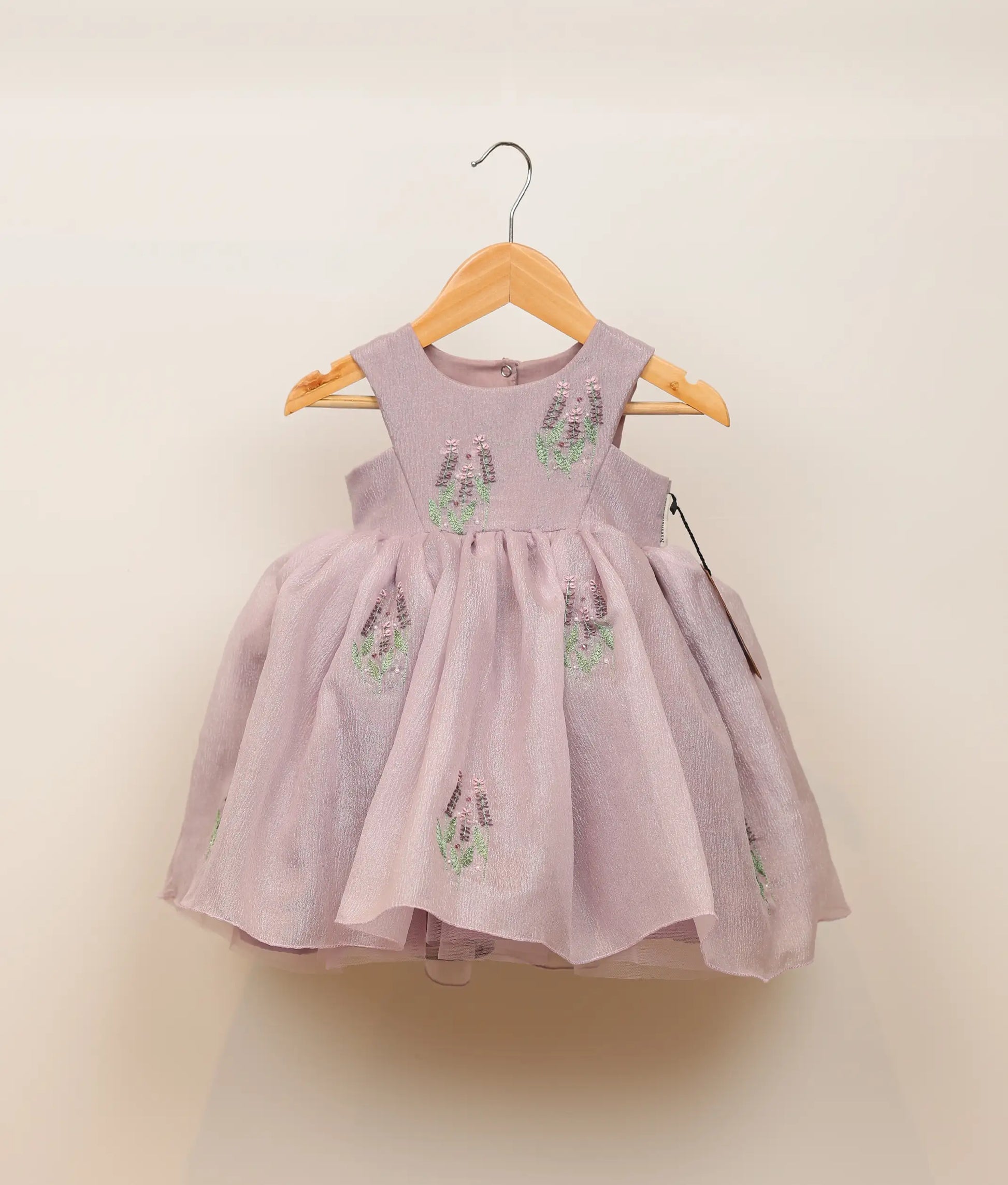 Front view of pastel lavender crush organza floral embroidery with handwork birthday frock against plain background 