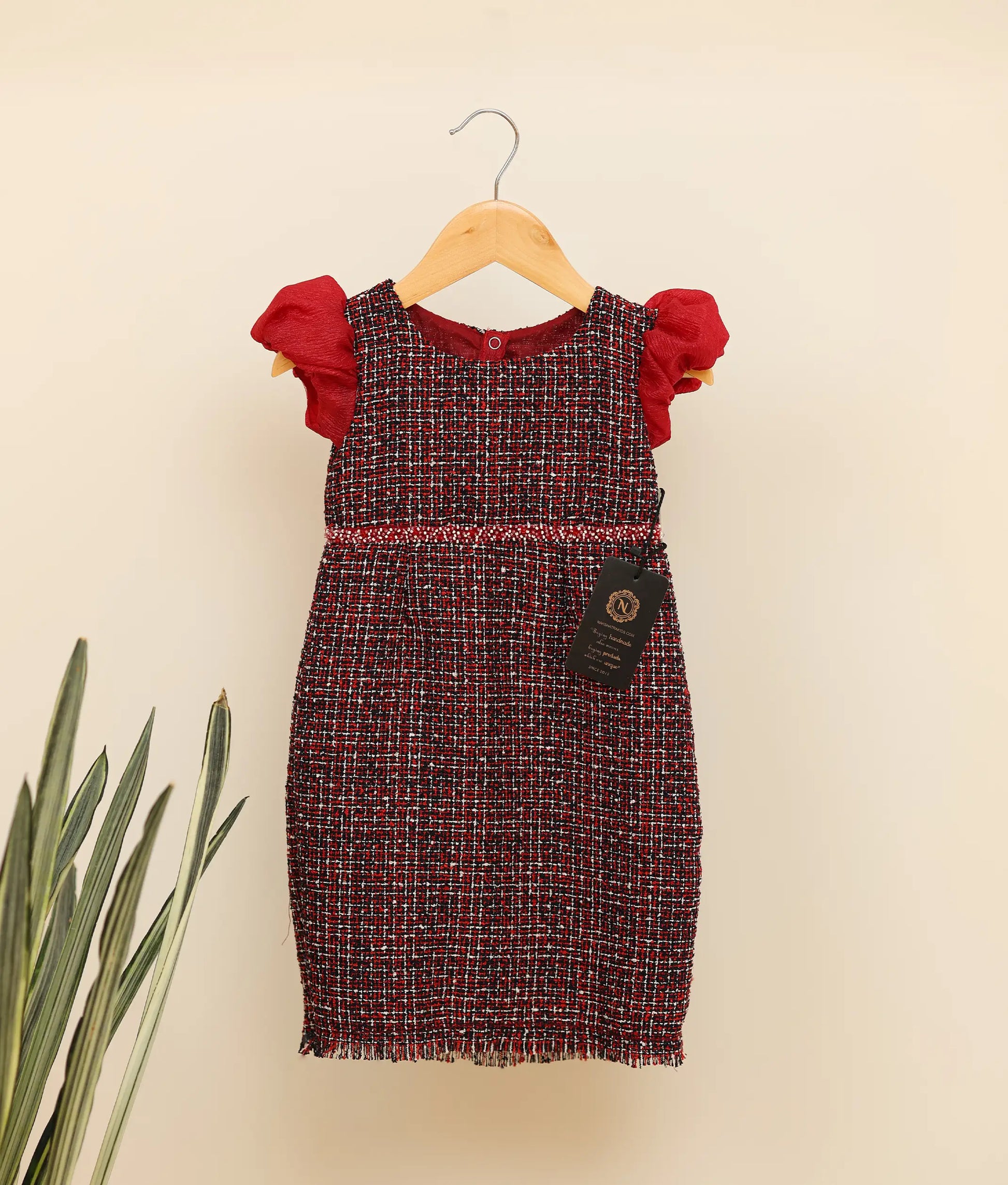 Front view of black handworked tweed handworked fish-cut frock against plain background 