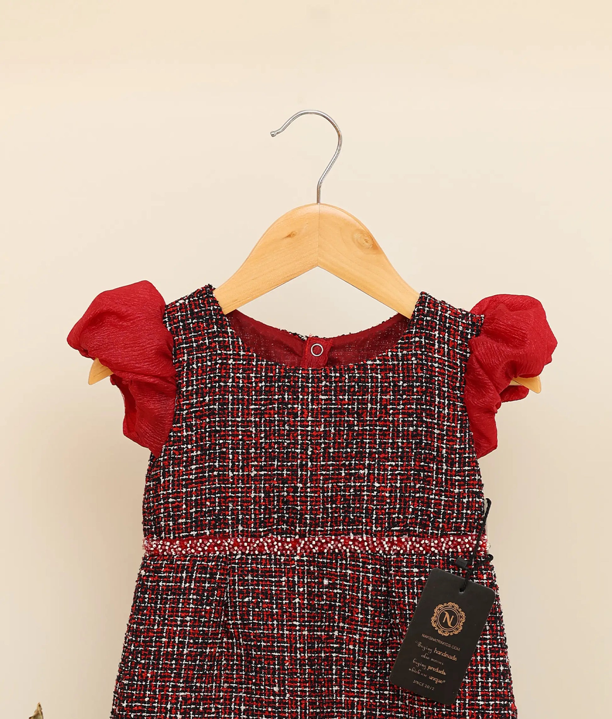 Close view of a black handworked tweed handworked fish-cut frock against plain background 