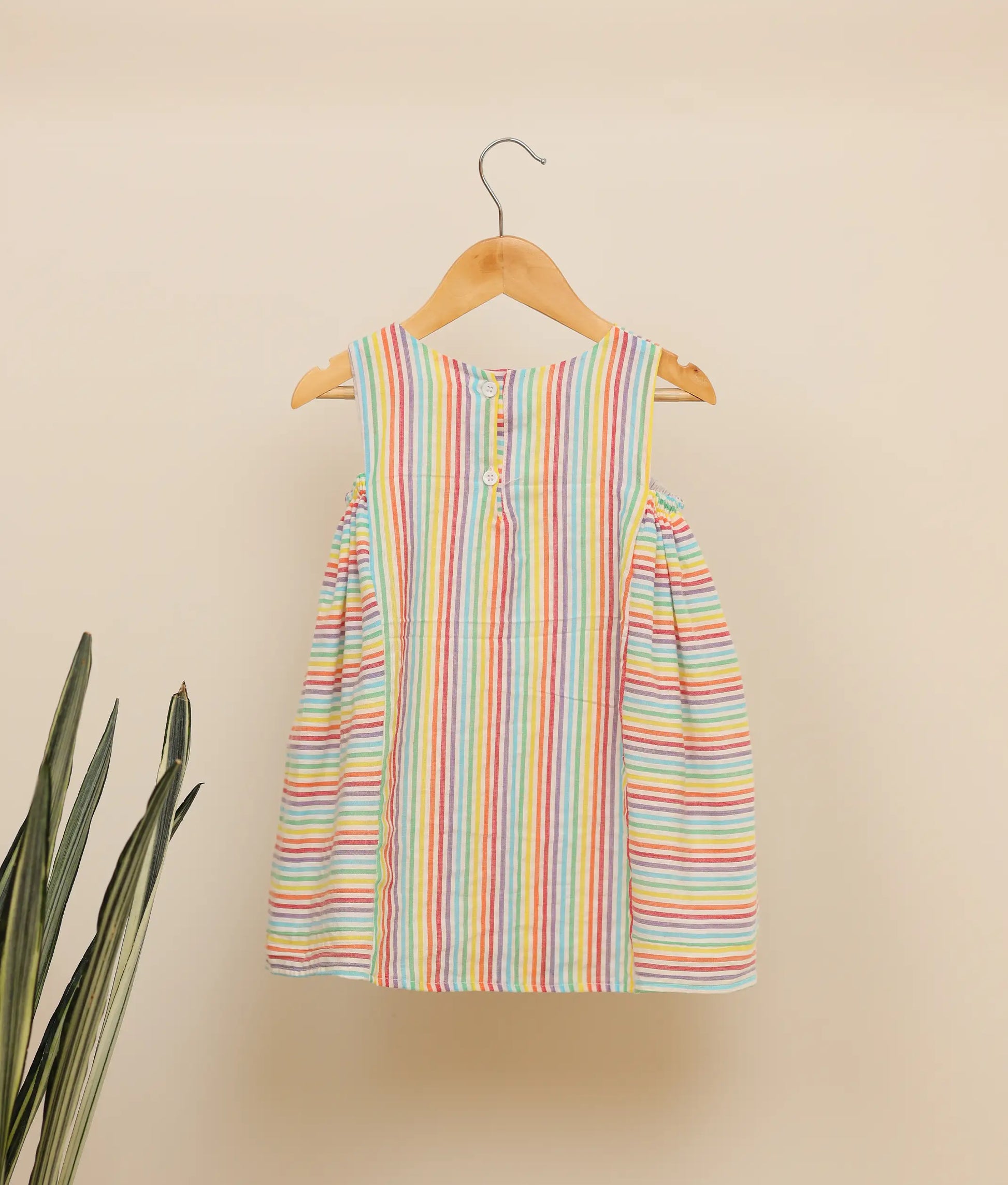 Back view of a multi-lined cotton Christmas frock against plain background