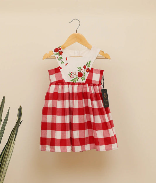 Front view of red check cotton floral painting Christmas frock against plain background.