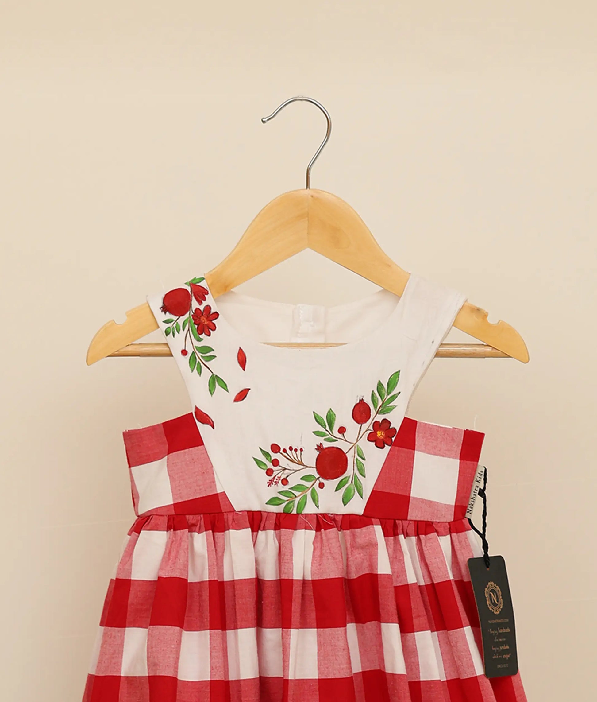 Close view of red check cotton floral painting Christmas frock against plain background