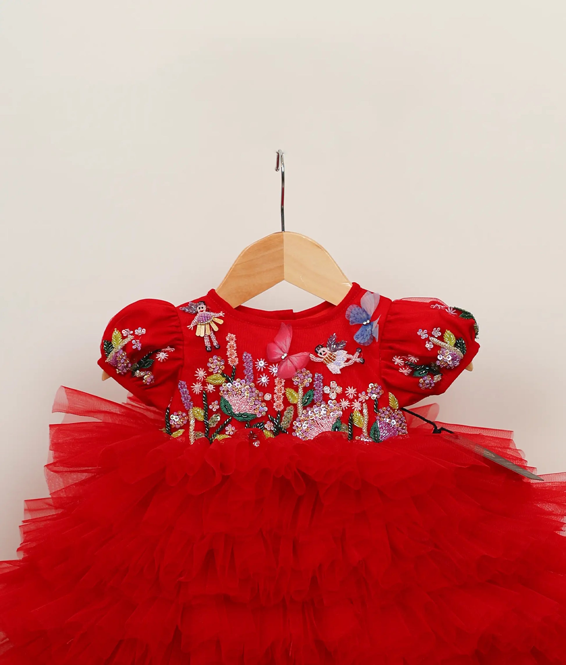 Close view of a red tulle net butterfly-themed step birthday dress against plain background