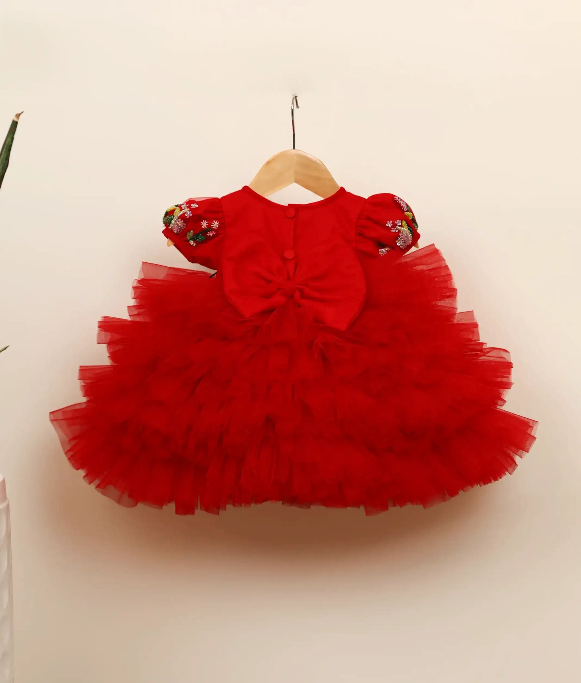 Back view of red tulle net butterfly-themed step birthday dress against plain background