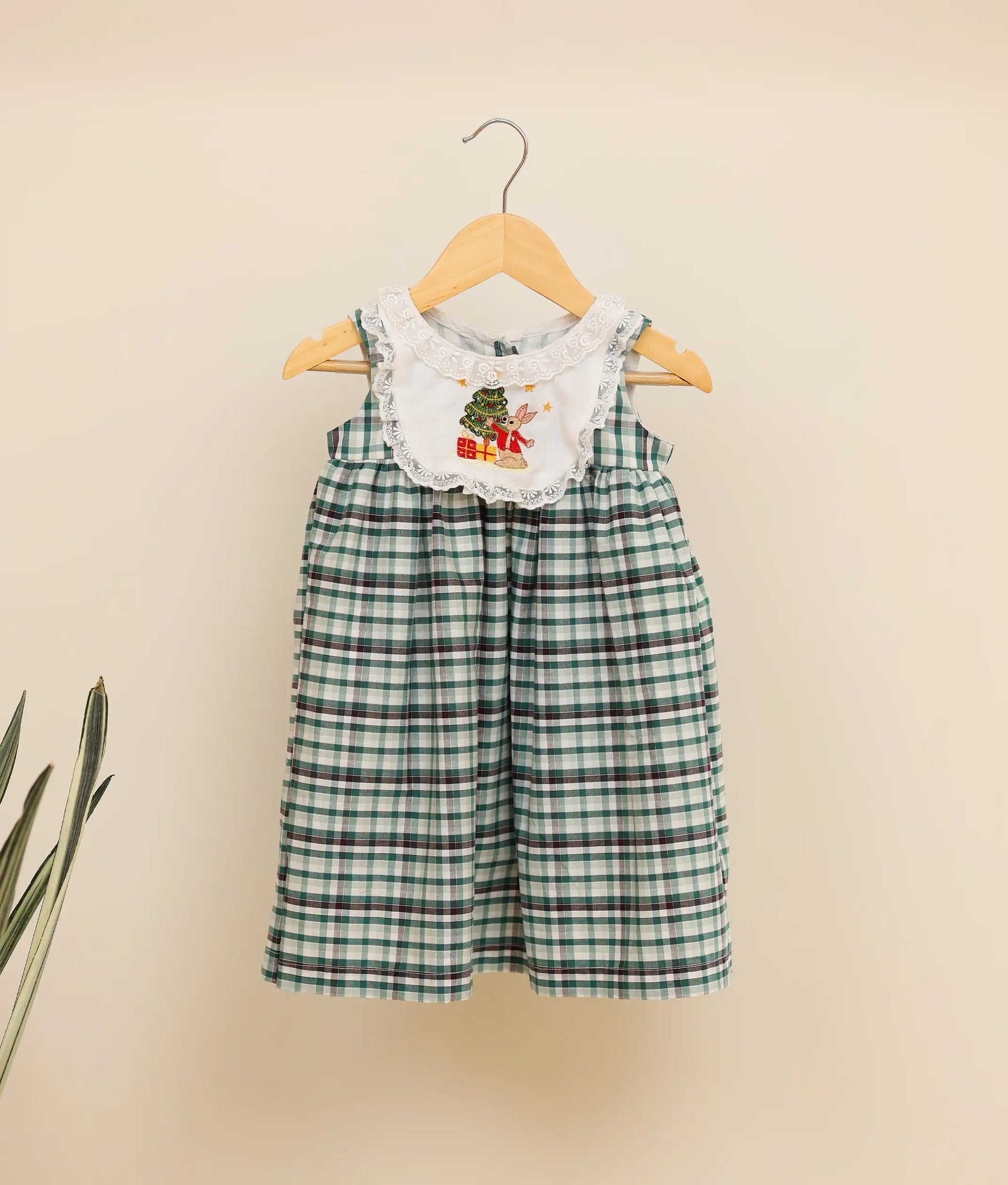 Front view of a green-check-embroidered cotton frock against plain background