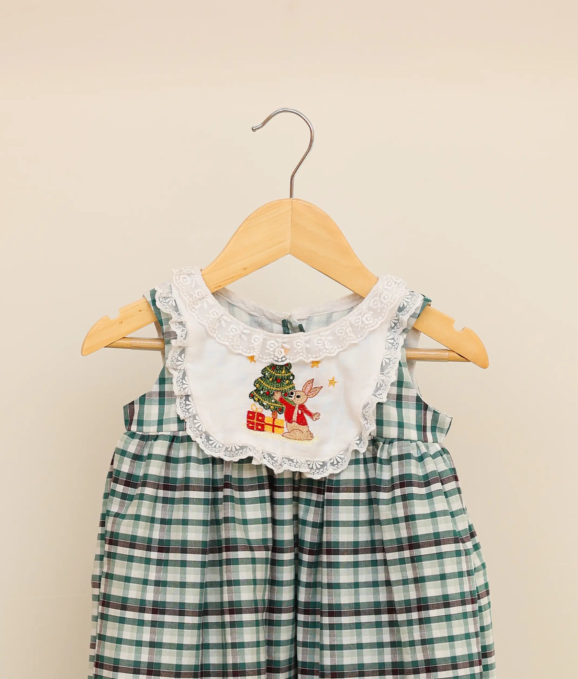 Close view of a green-check-embroidered cotton frock against plain background
