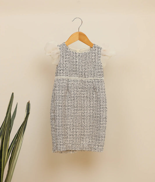 Front view of black and white handworked tweed-fish cut frock against plain background 