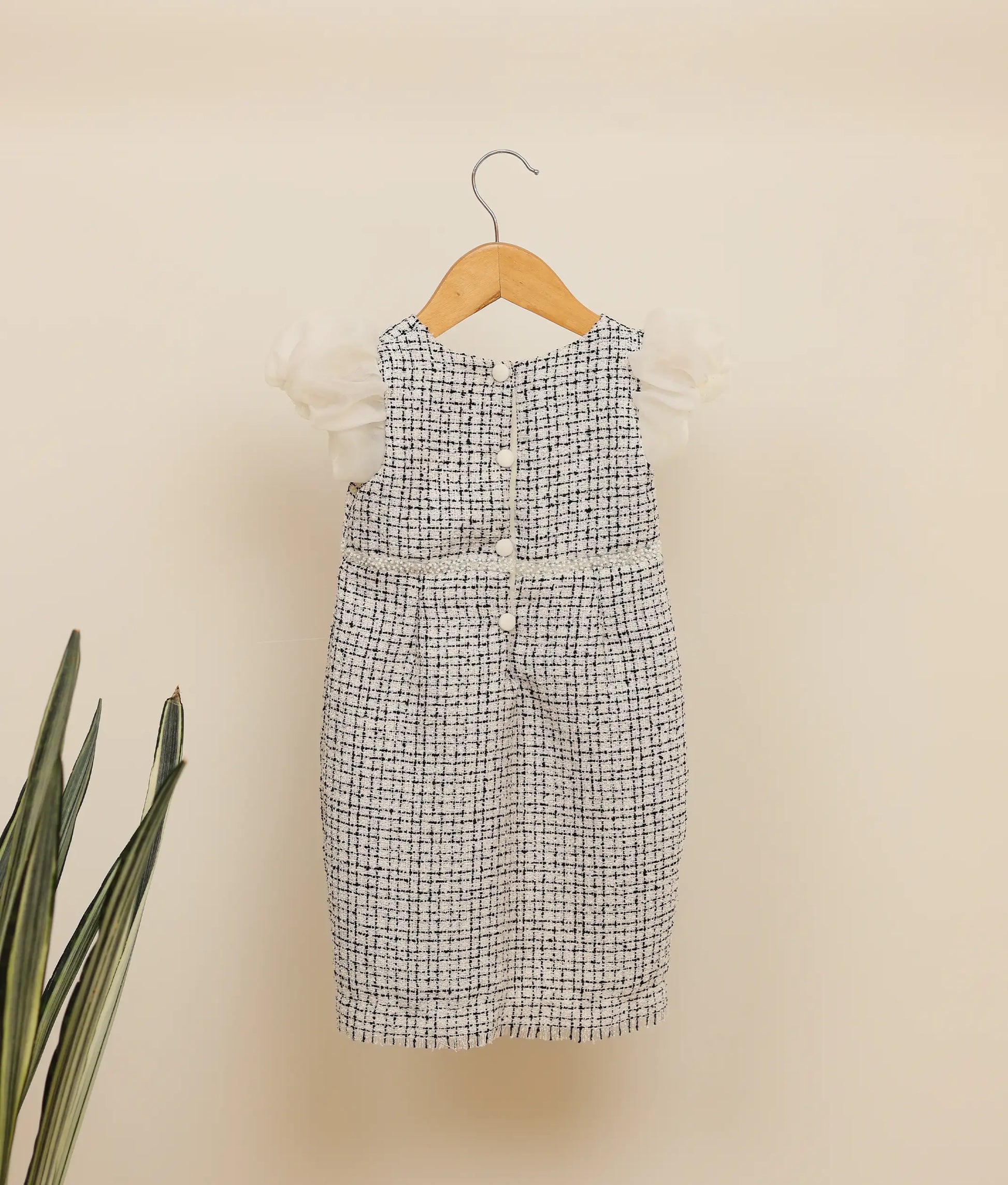 Back view of black and white handworked tweed-fish cut frock against plain background 