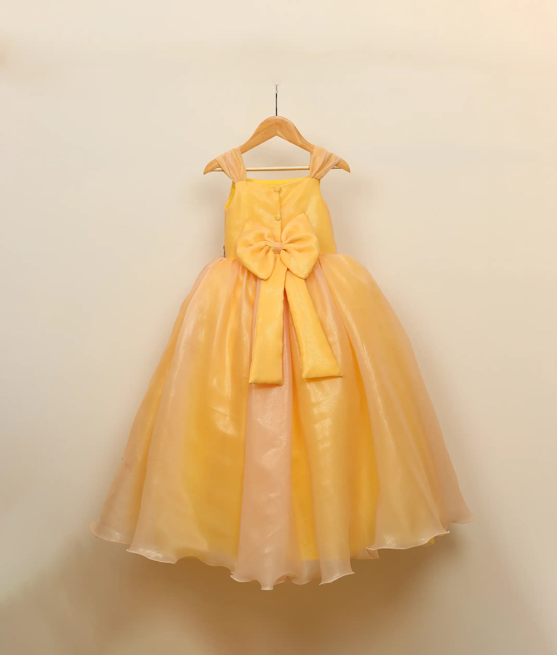 Back view of Golden yellow jungle-themed birthday gown against plain background