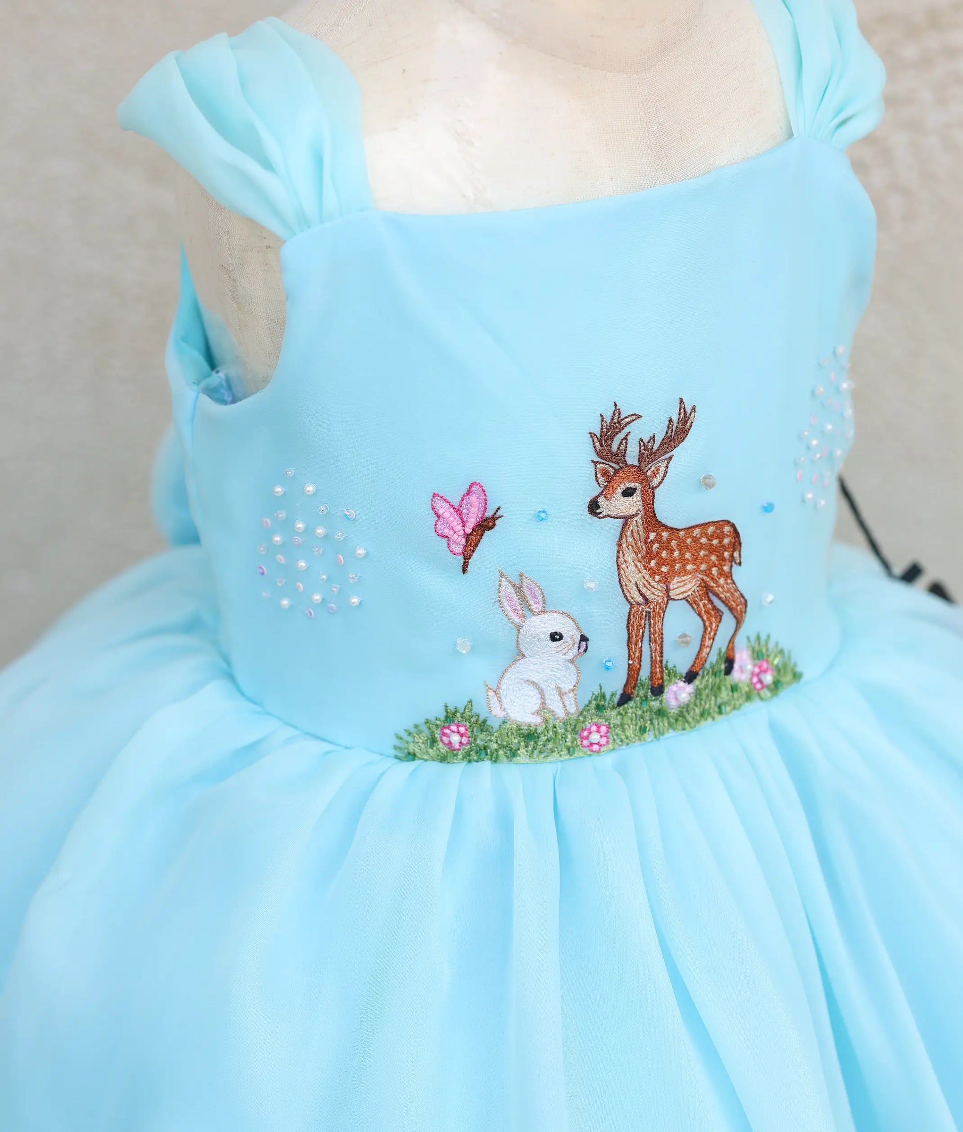 Close view of plain organza deer- and rabbit-themed birthday gown