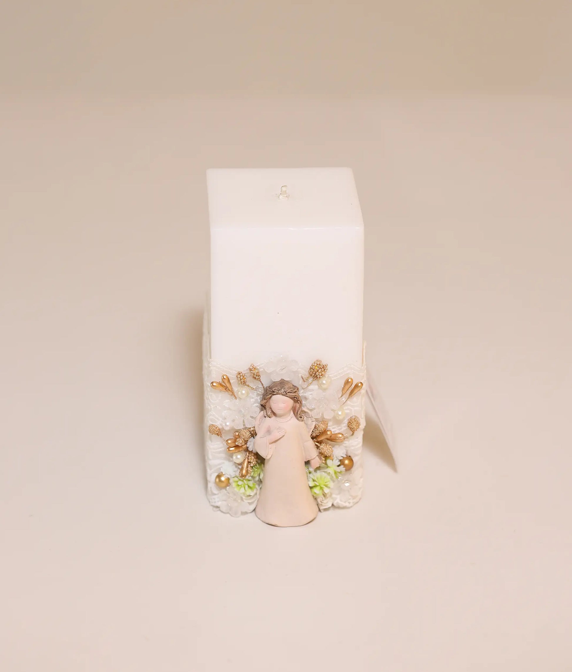 Close view of off-white decorative angel pillar candle against plain background