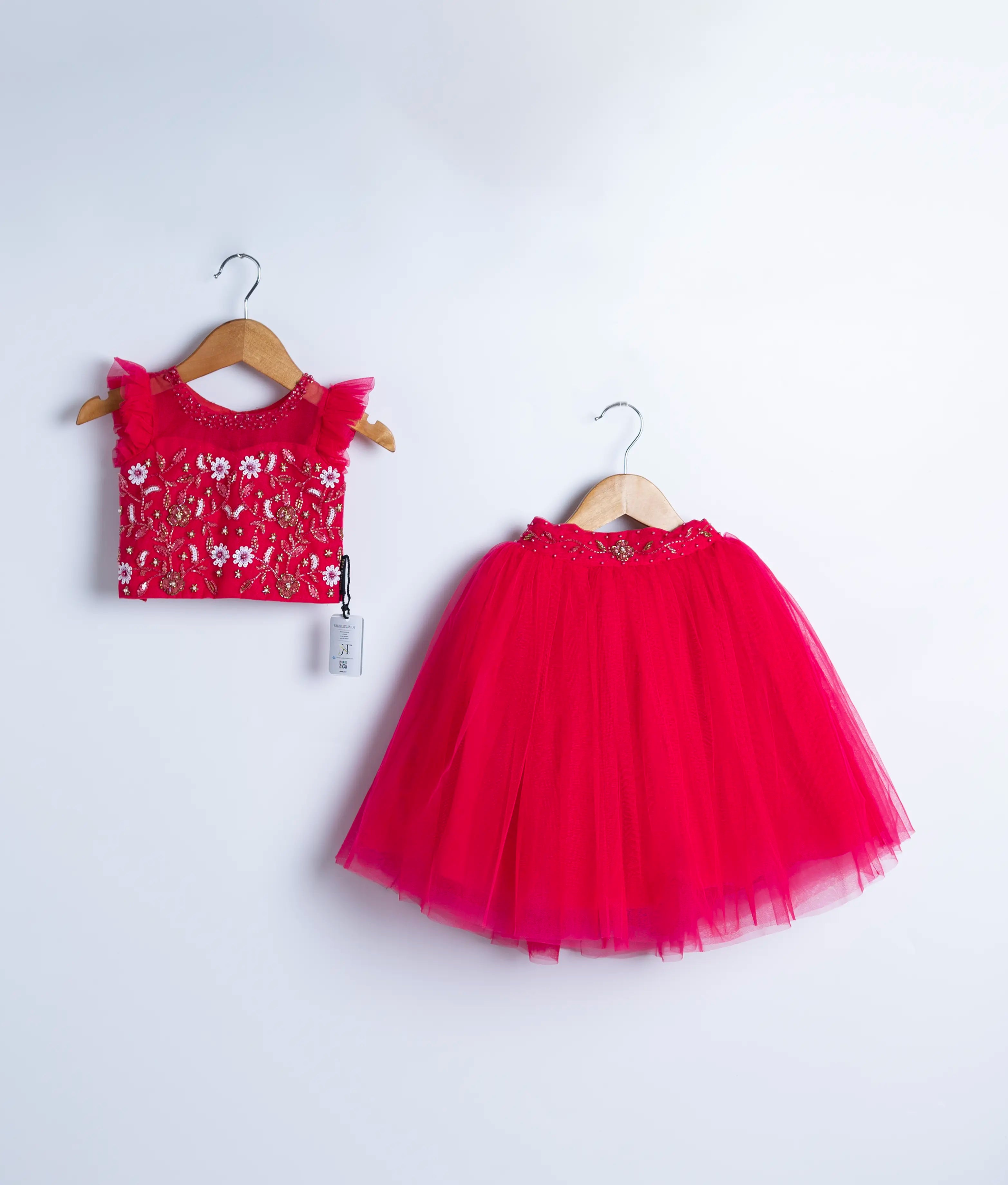 A hot pink tulle net crop top full skirt displayed on a hanger.