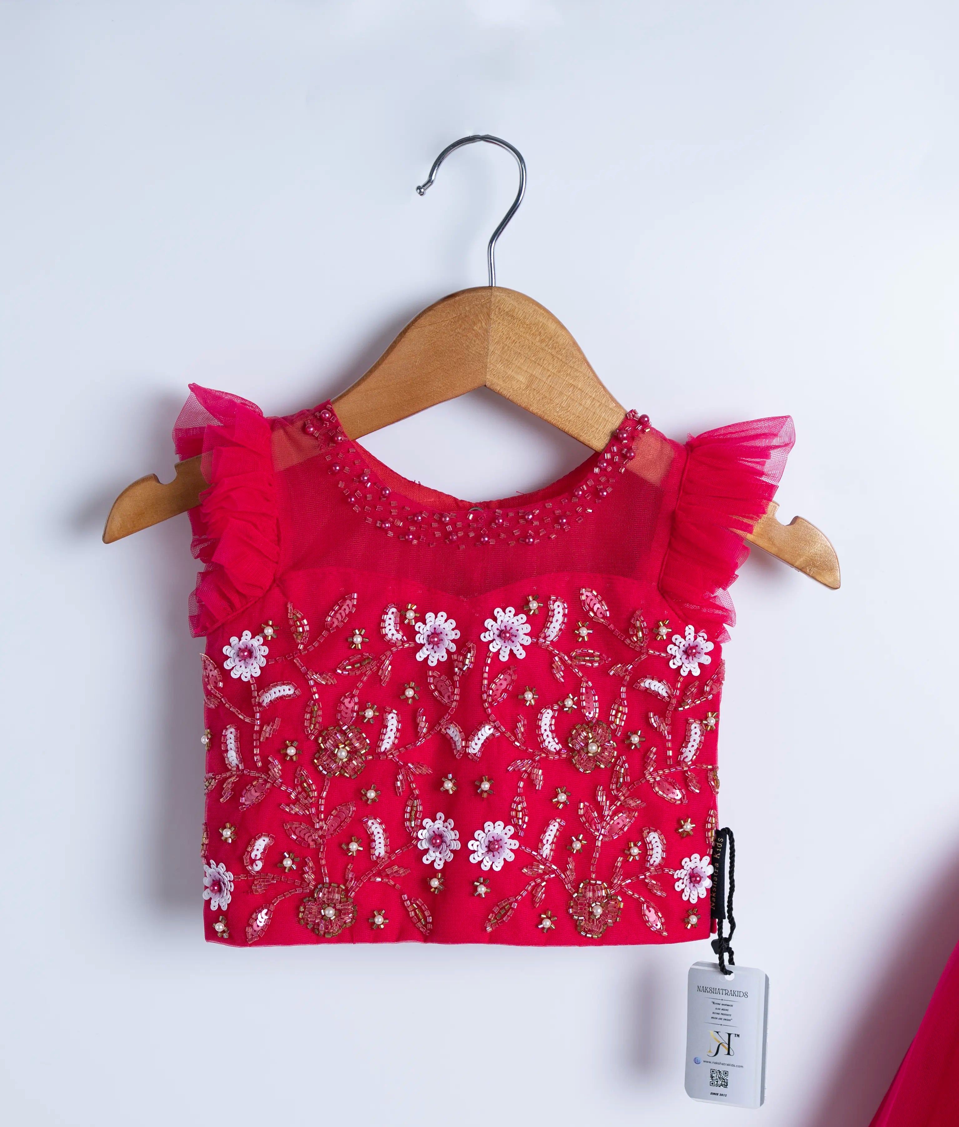 Close view of an hot pink tulle net crop top full skirt displayed on a hanger.