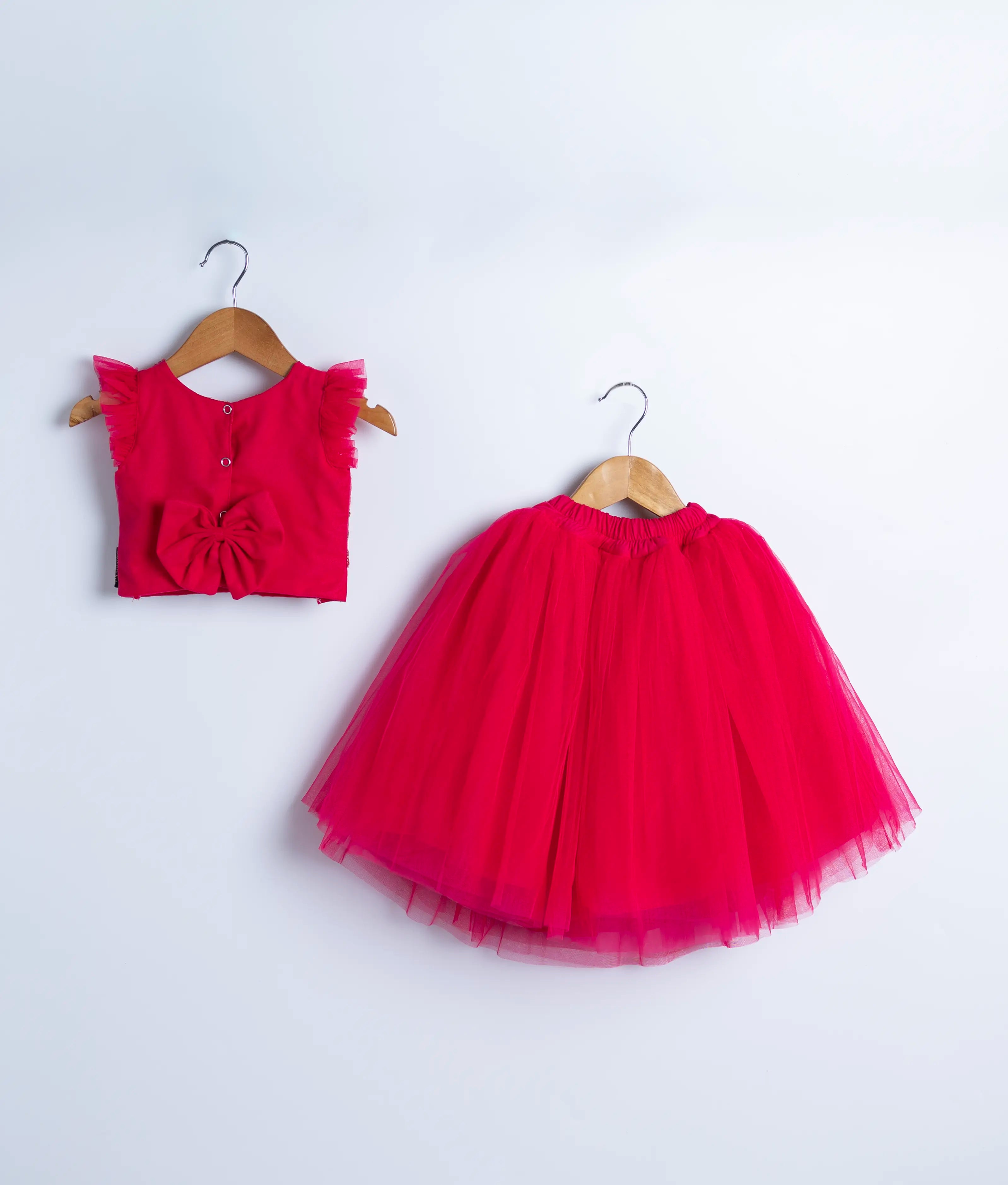 Back view of an hot pink tulle net crop top full skirt displayed on a hanger.