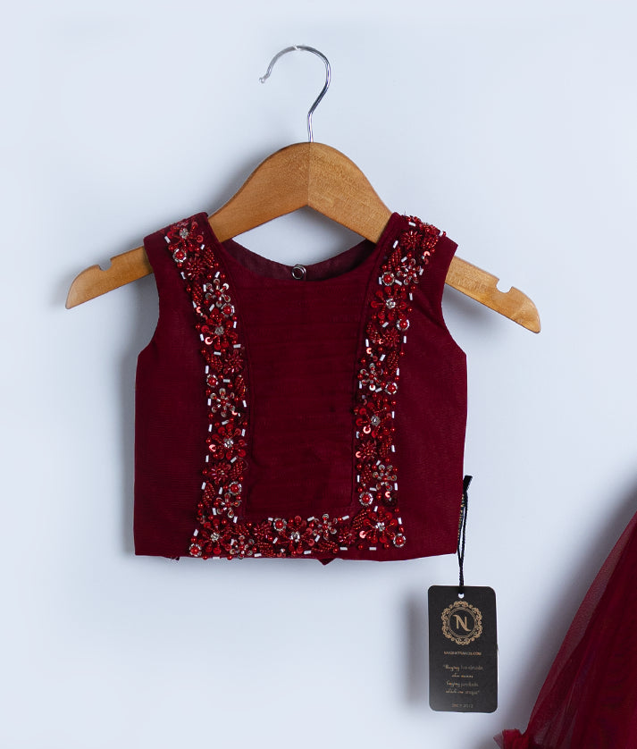 Close view of an maroon tulle net handworked skirt and top set displayed against a white background.