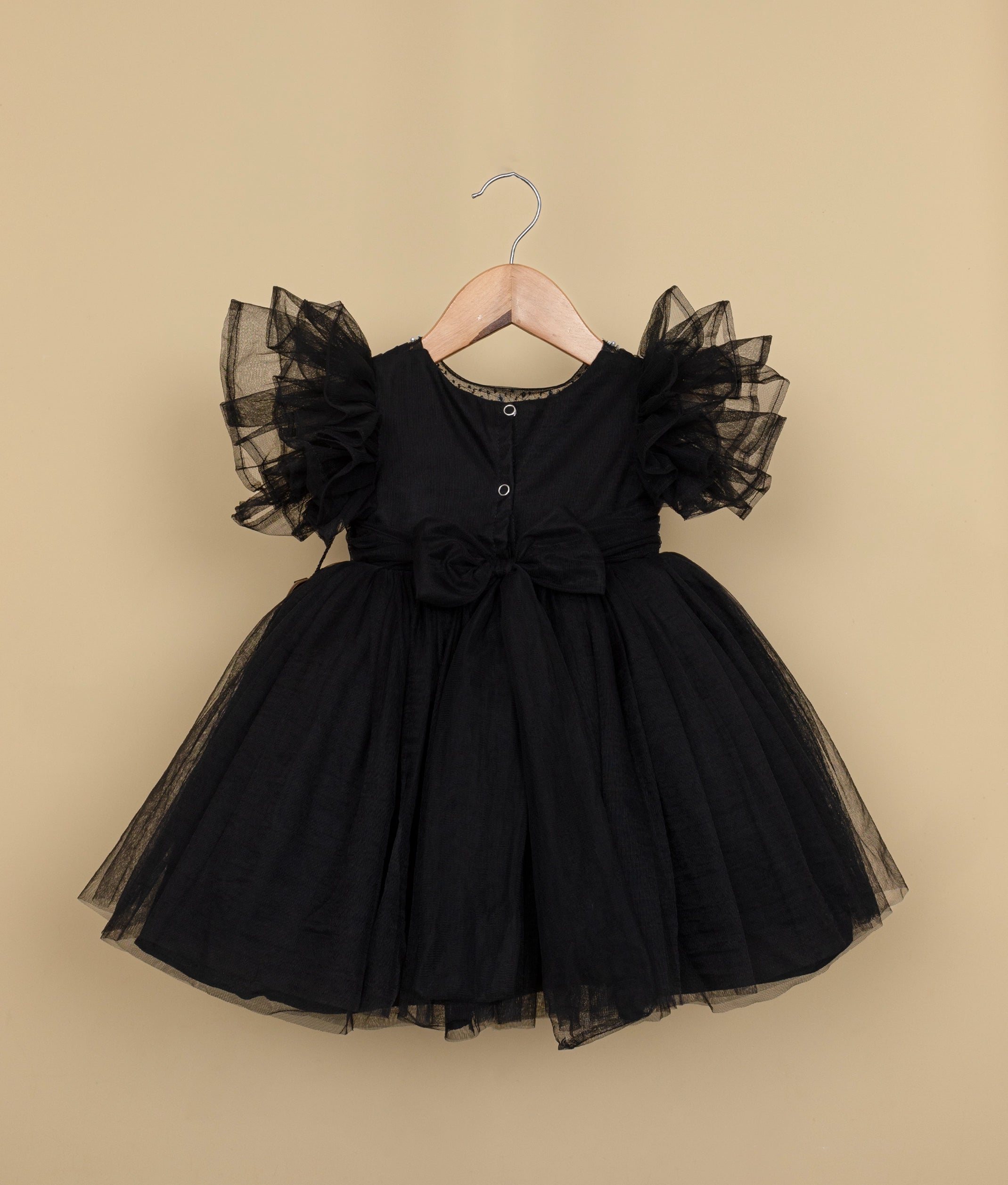 Back view of a black tulle net birthday frock displayed on a hanger.