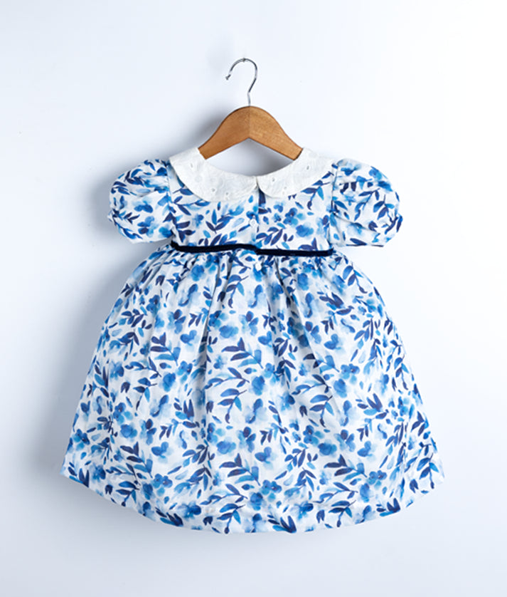Back view of an white and blue printed cotton frock displayed on a hanger.
